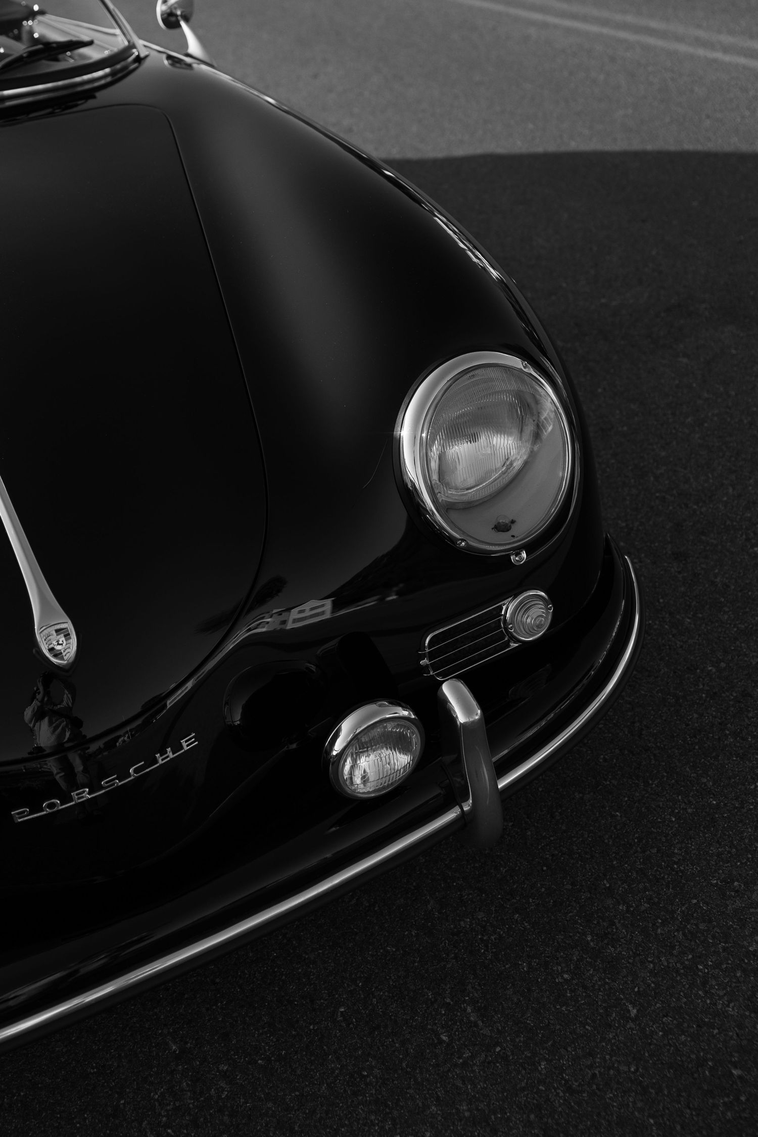 Close-up details of a sleek black vintage Porsche showing headlights and curves.