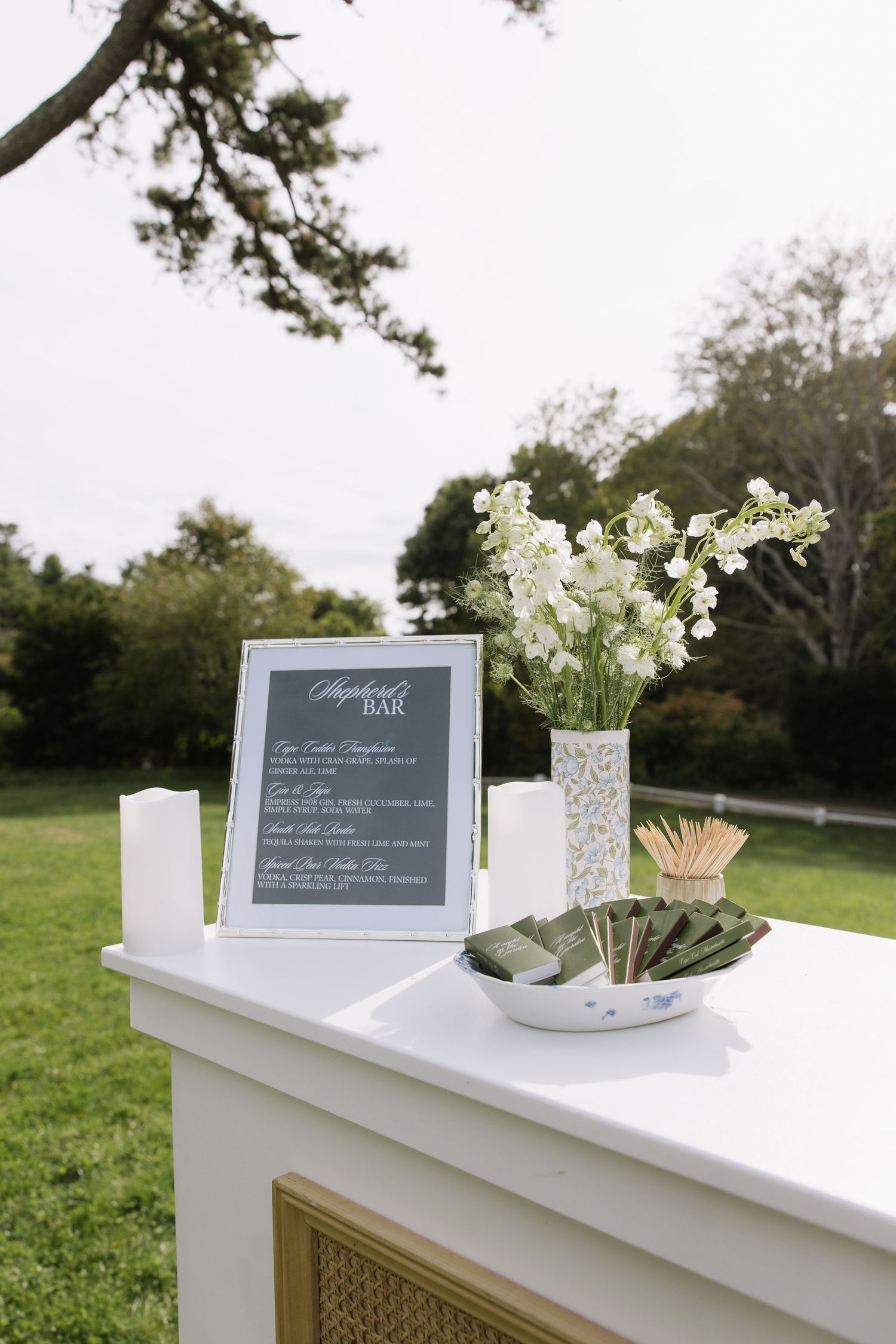 White decorative table setup with chalkboard signs and floral arrangements at an outdoor event.