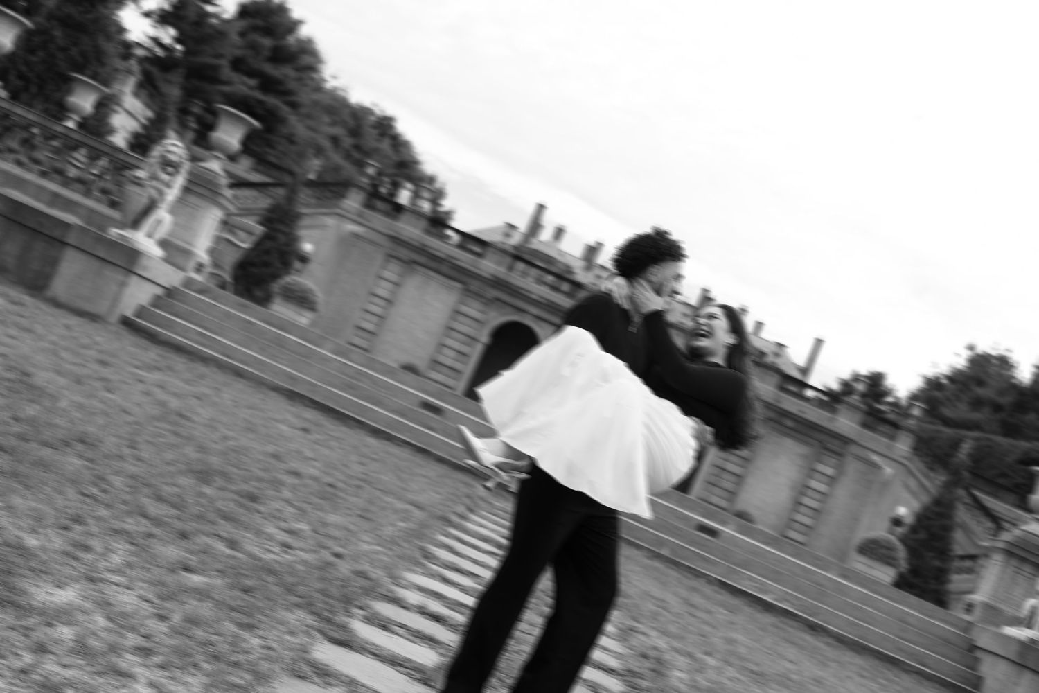 Artistic black and white photo of figures walking on expansive estate grounds.