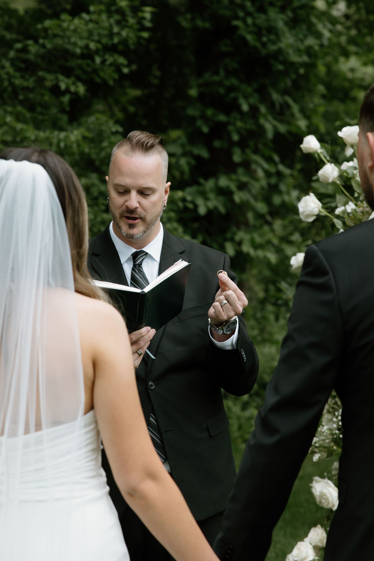 An officiant reads from a book during an intimate outdoor wedding ceremony.