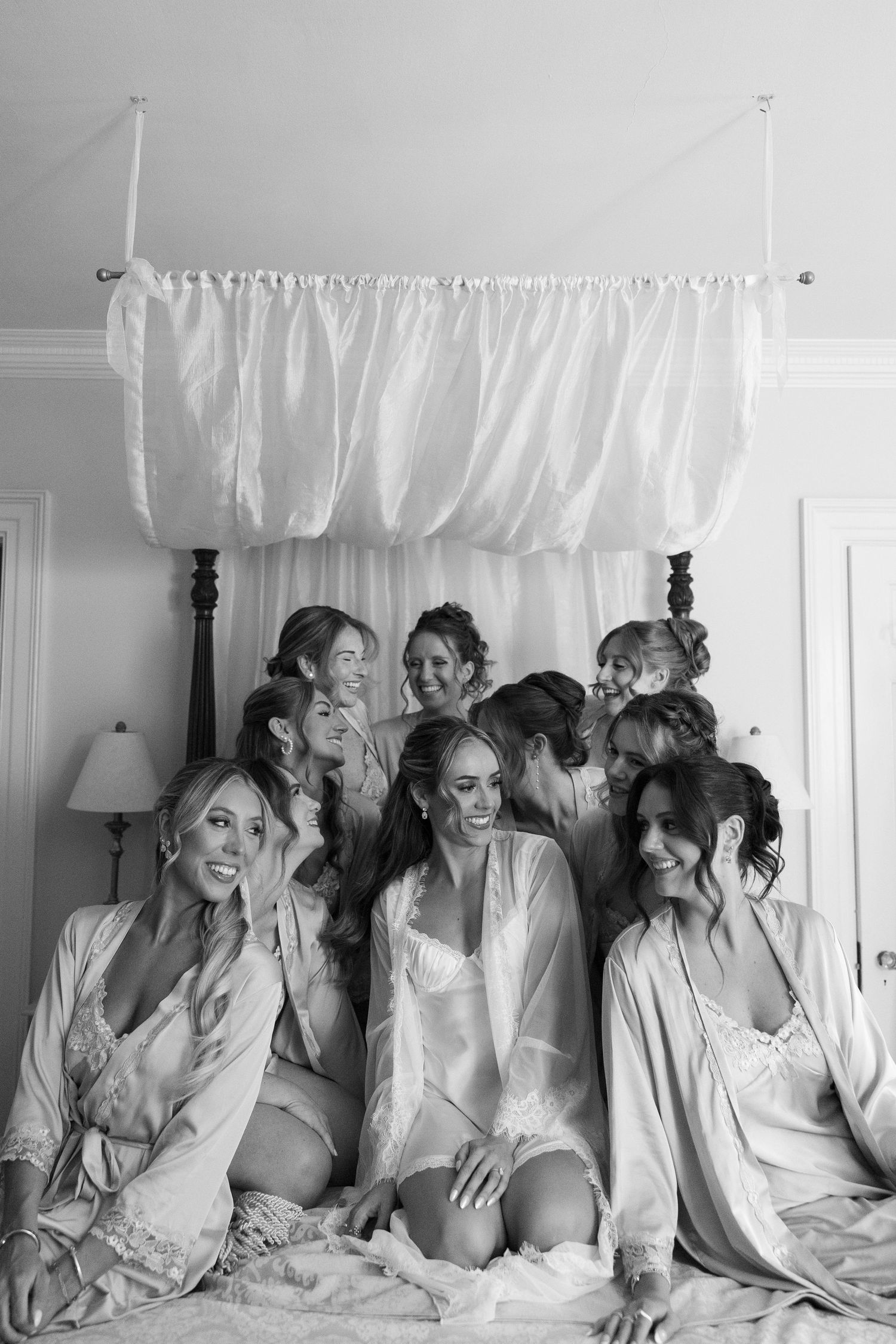 Wedding party in white robes shares candid moment during pre-ceremony preparations.
