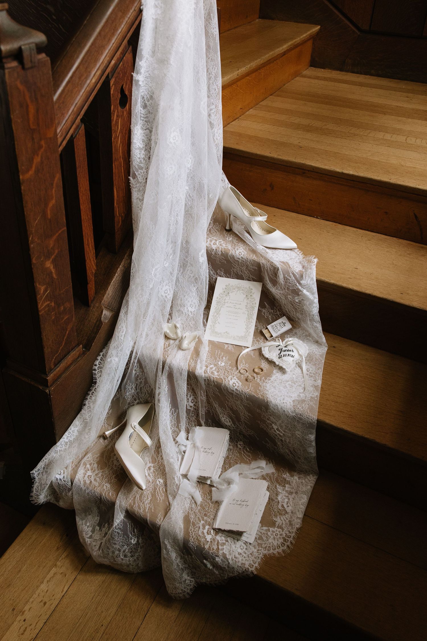 White wedding veil draped over wooden stairs with scattered envelopes and cards creating a romantic vintage scene.