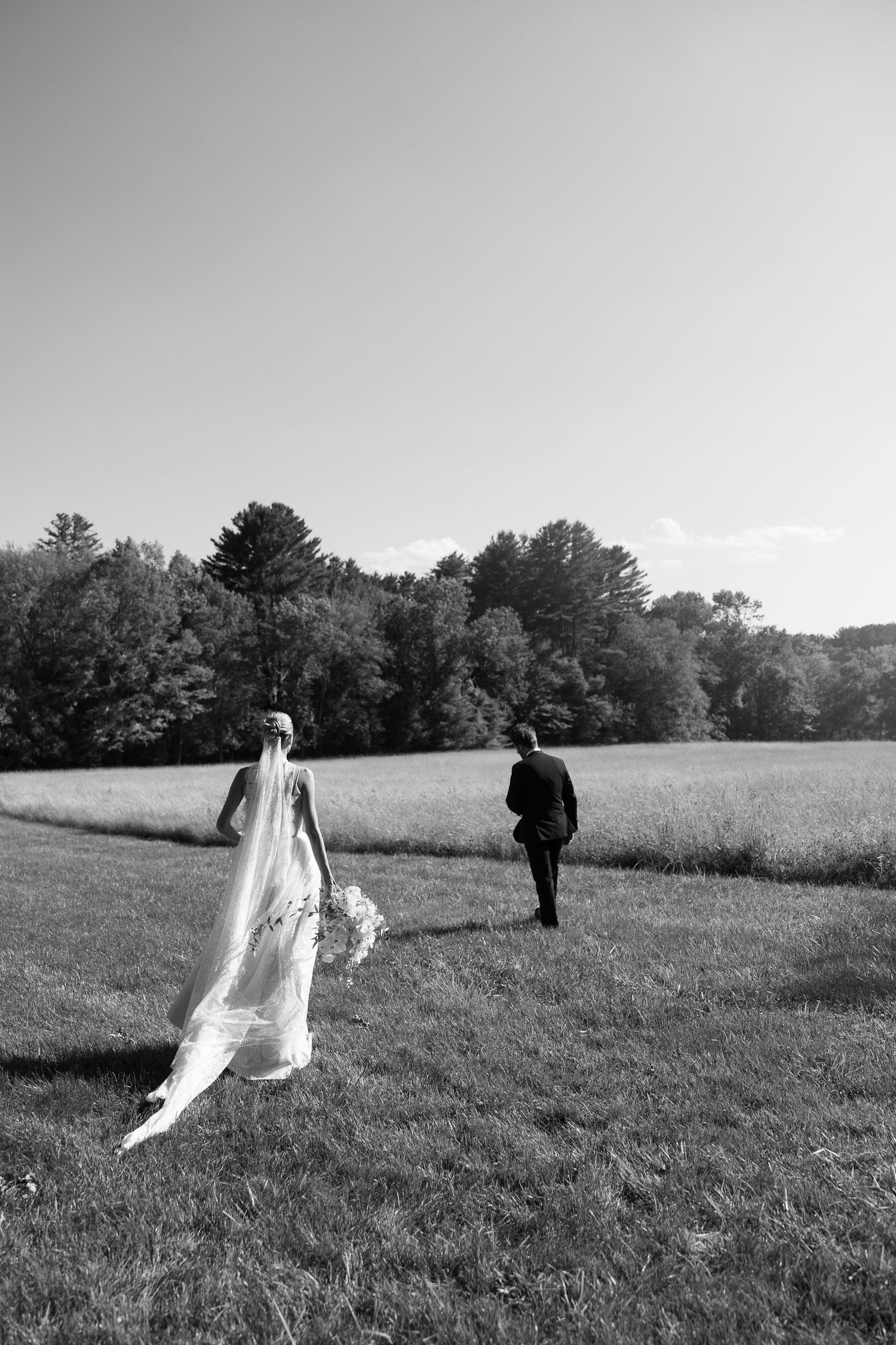 Black and white photo of figures walking through an open field.