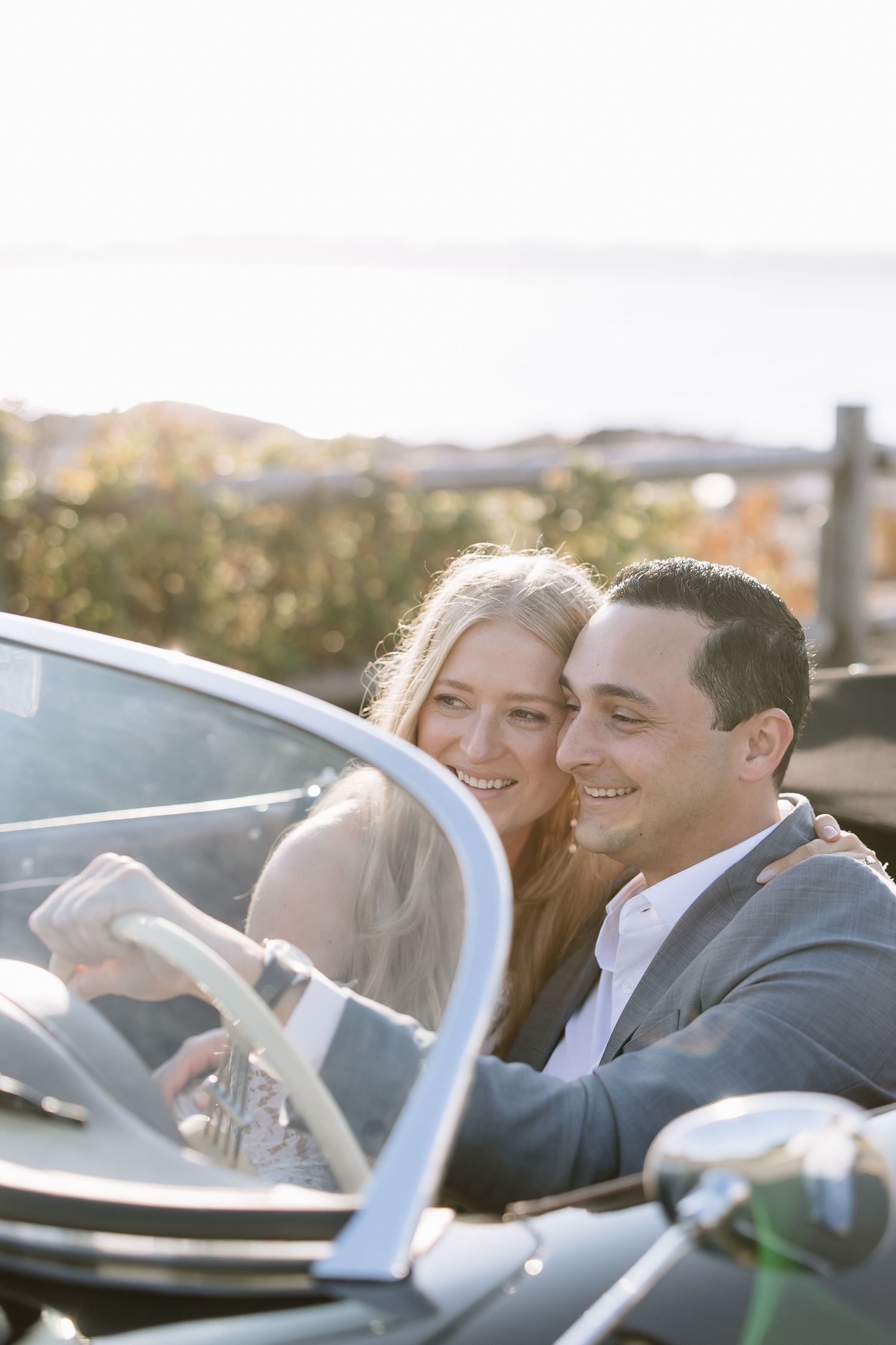 A couple laughs together while seated in a classic black convertible car.