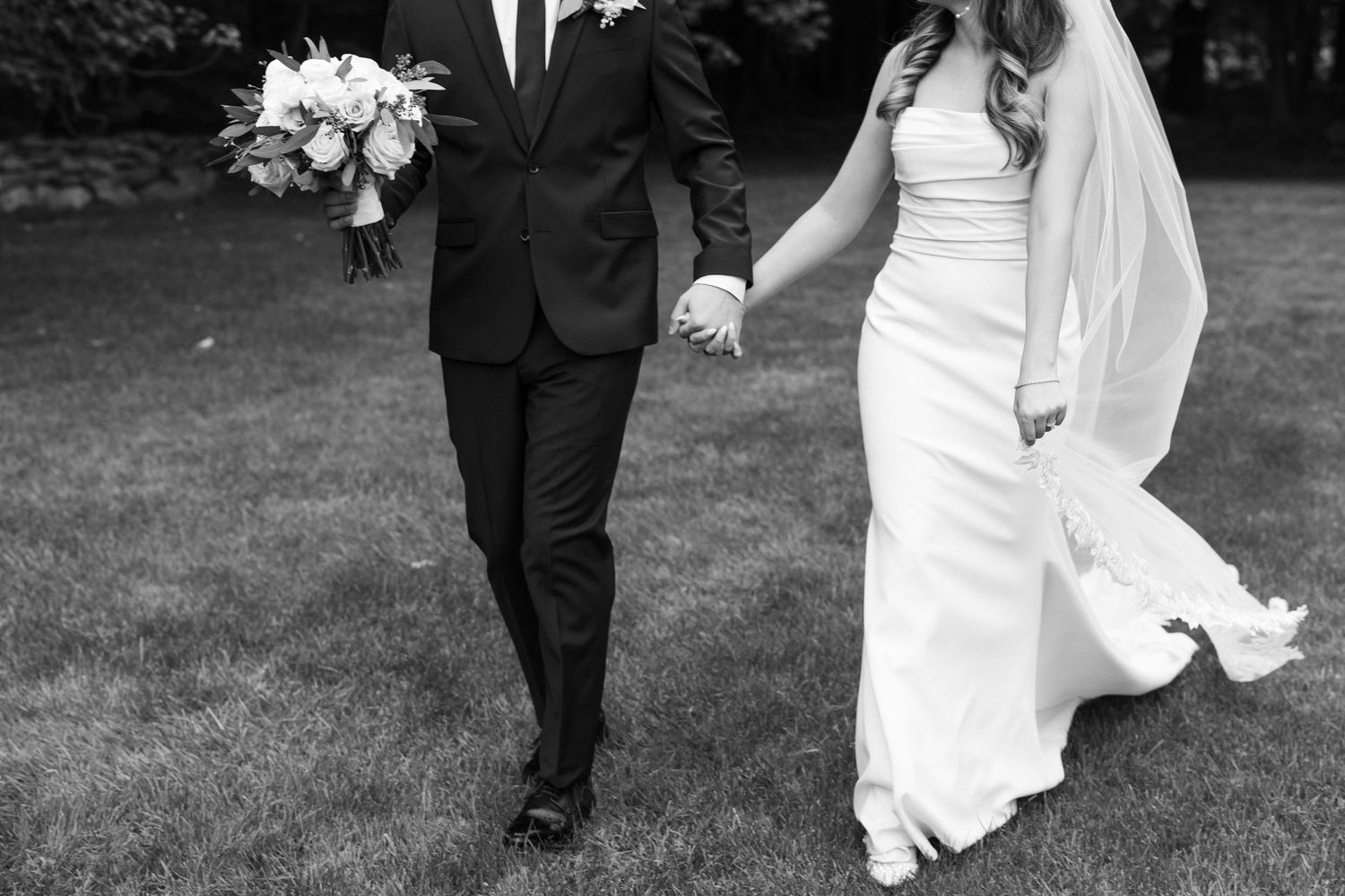 A couple walks together through a garden setting on their wedding day.