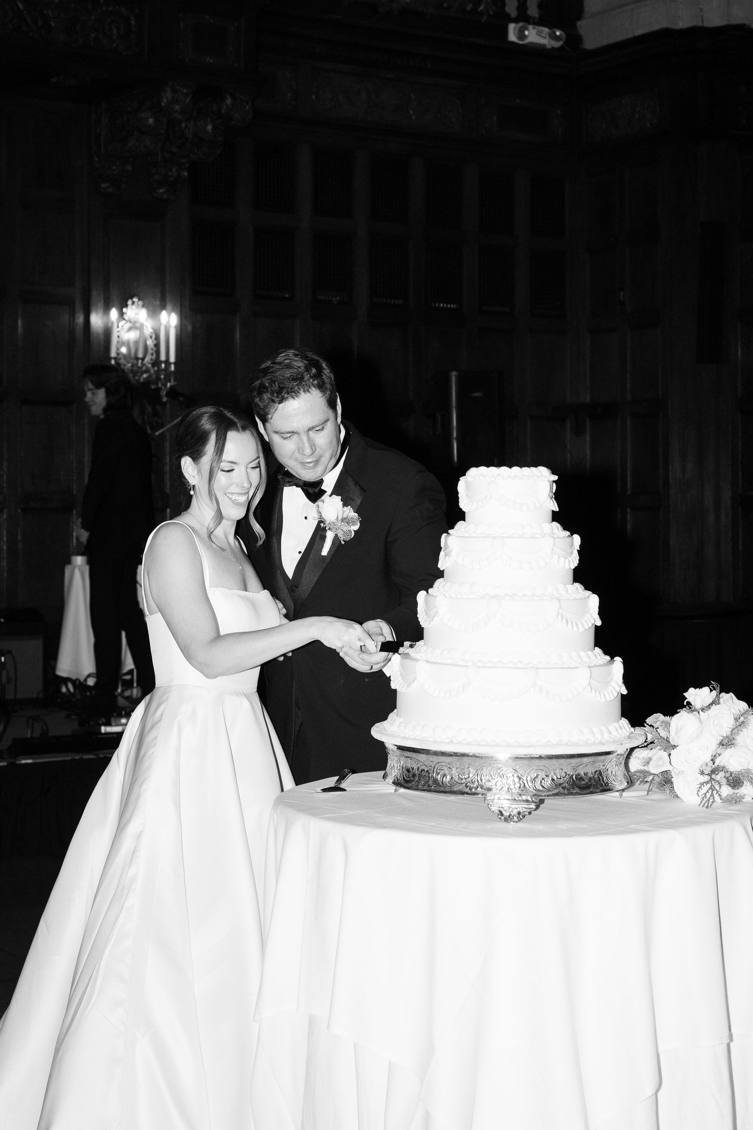 Wedding couple cuts their elegant white tiered cake during the reception celebration.