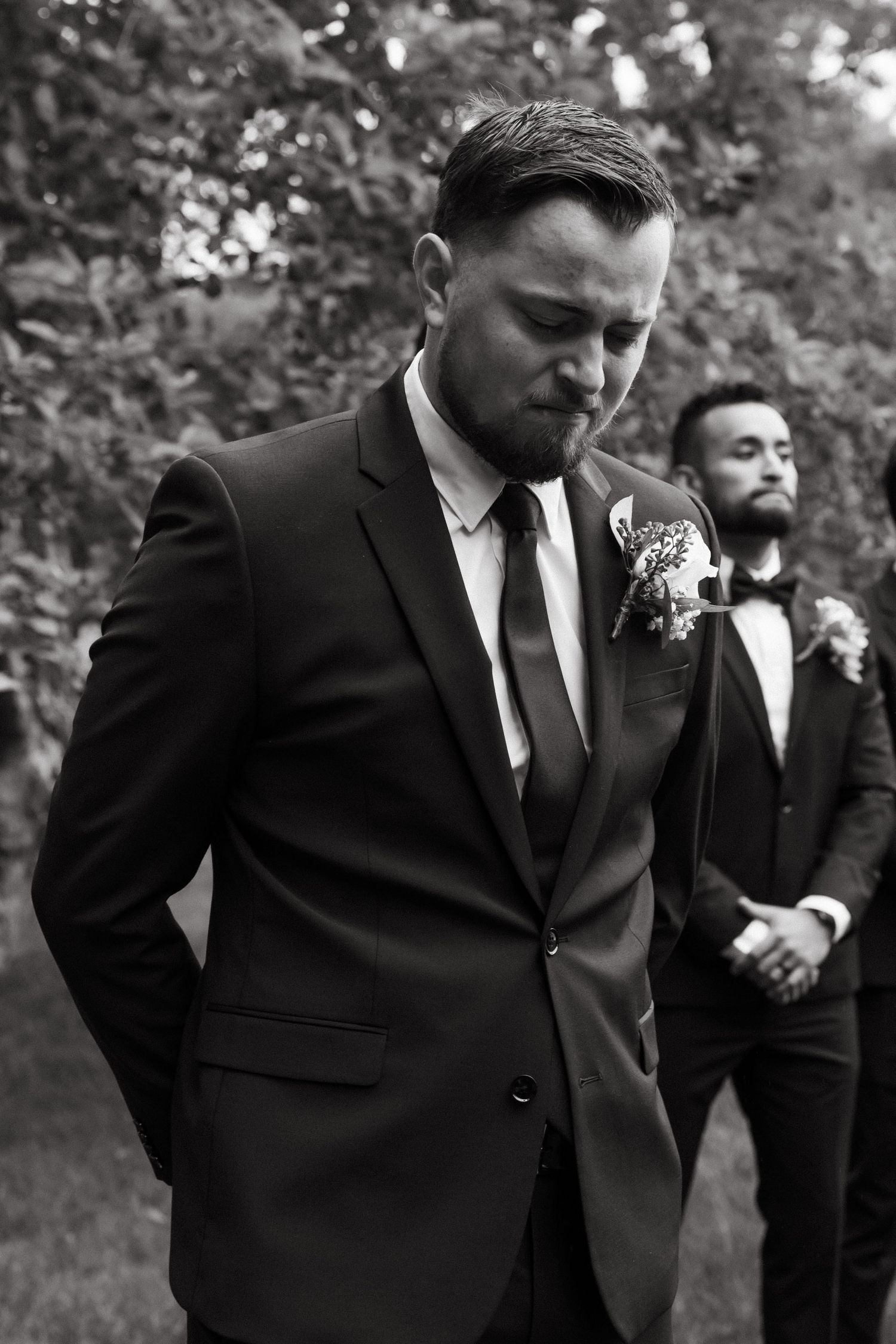 Groomsmen in black suits showing emotion during wedding ceremony.