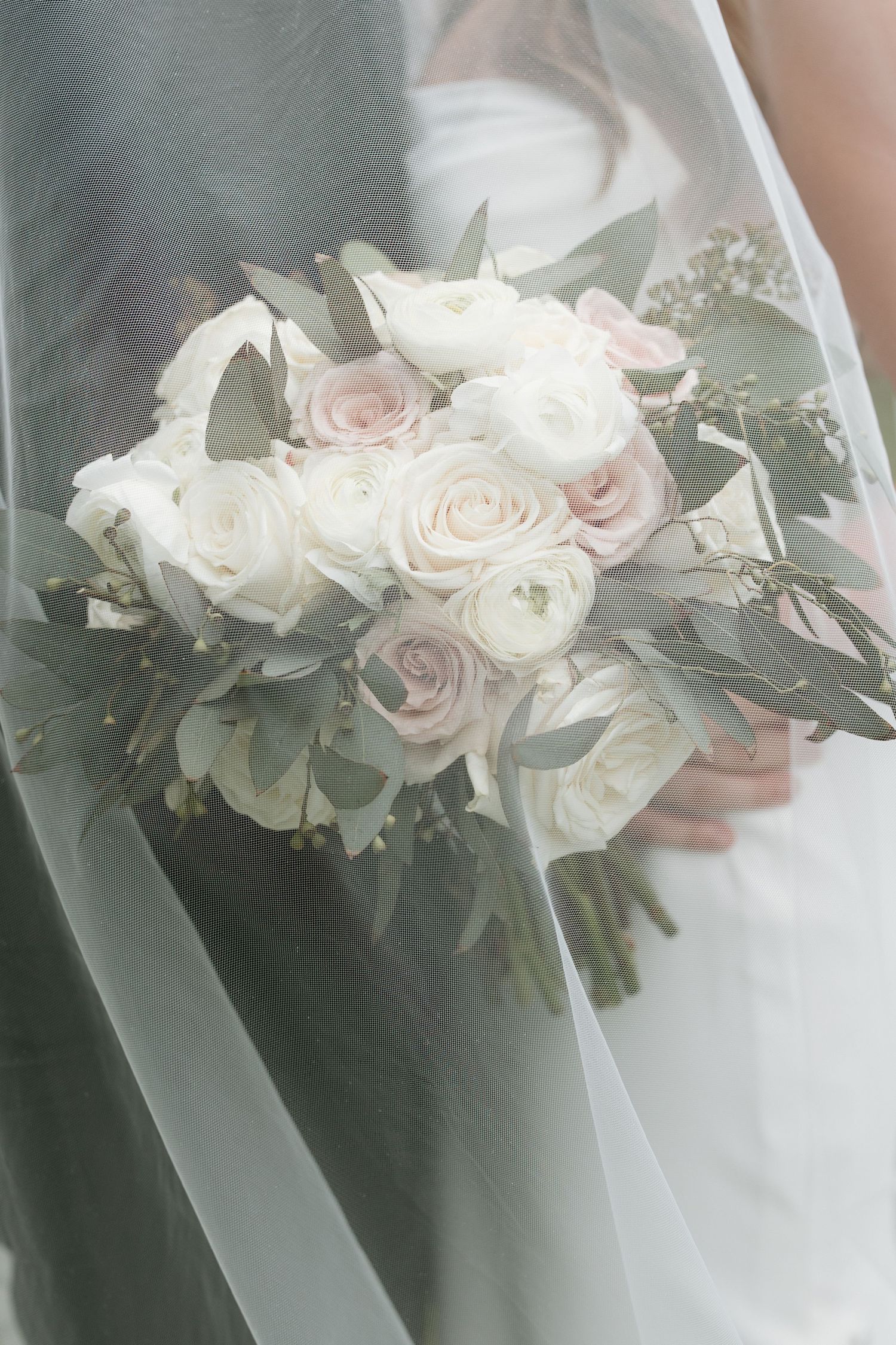 Elegant white and blush rose wedding bouquet with delicate greenery.