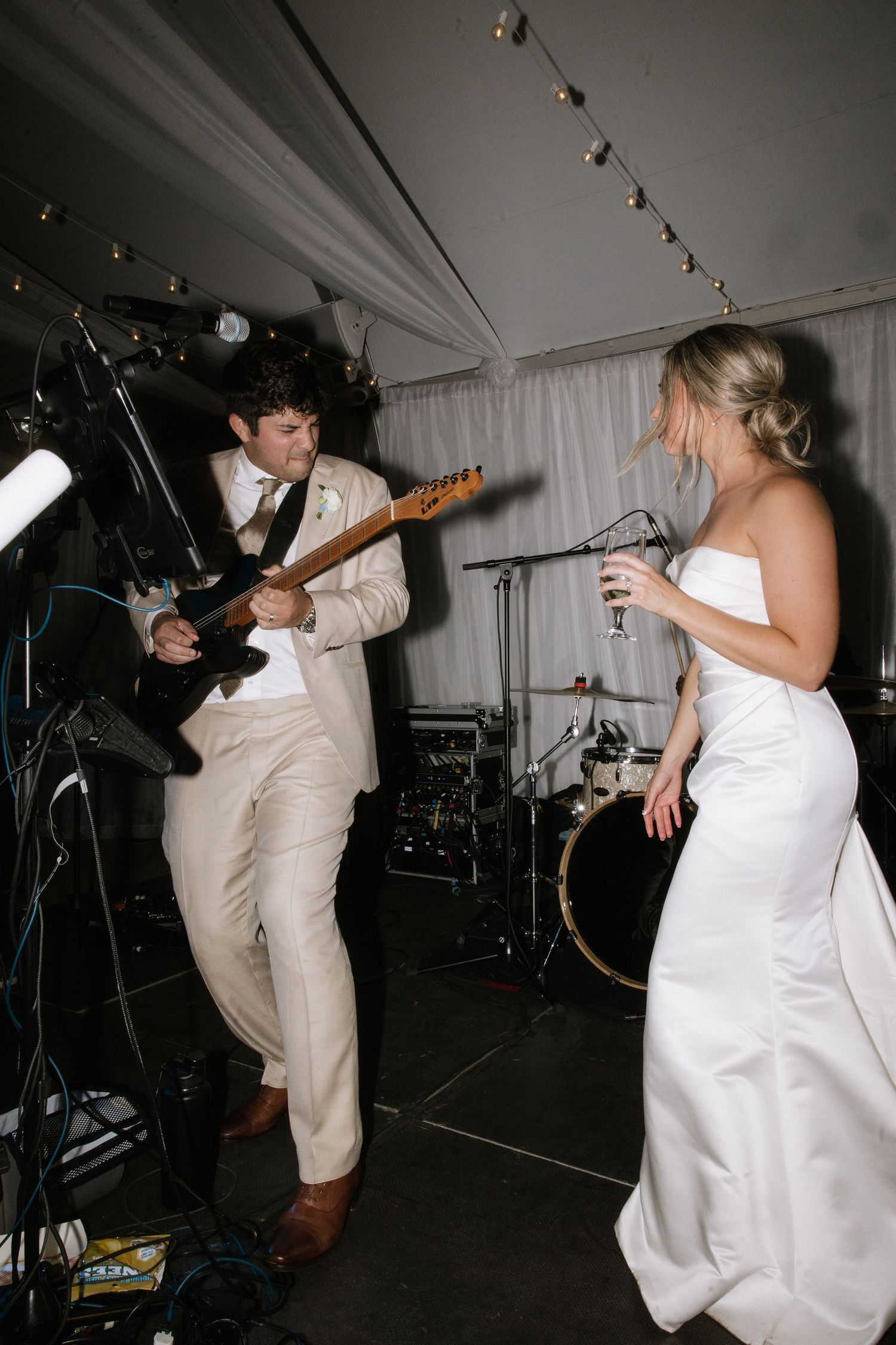 Reception performance with guitarist in light suit and person in white dress on dance floor.