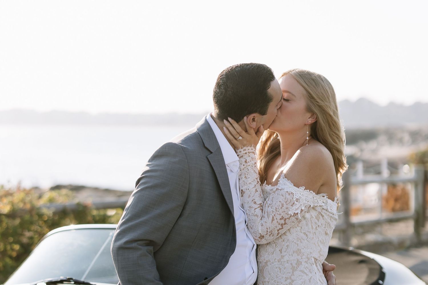 Romantic coastal photoshoot featuring elegant attire and vintage automobiles.