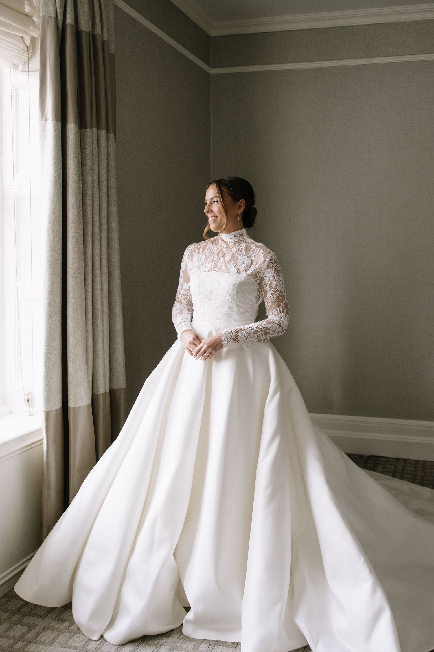 Elegant white wedding gown with lace details photographed in natural window light.