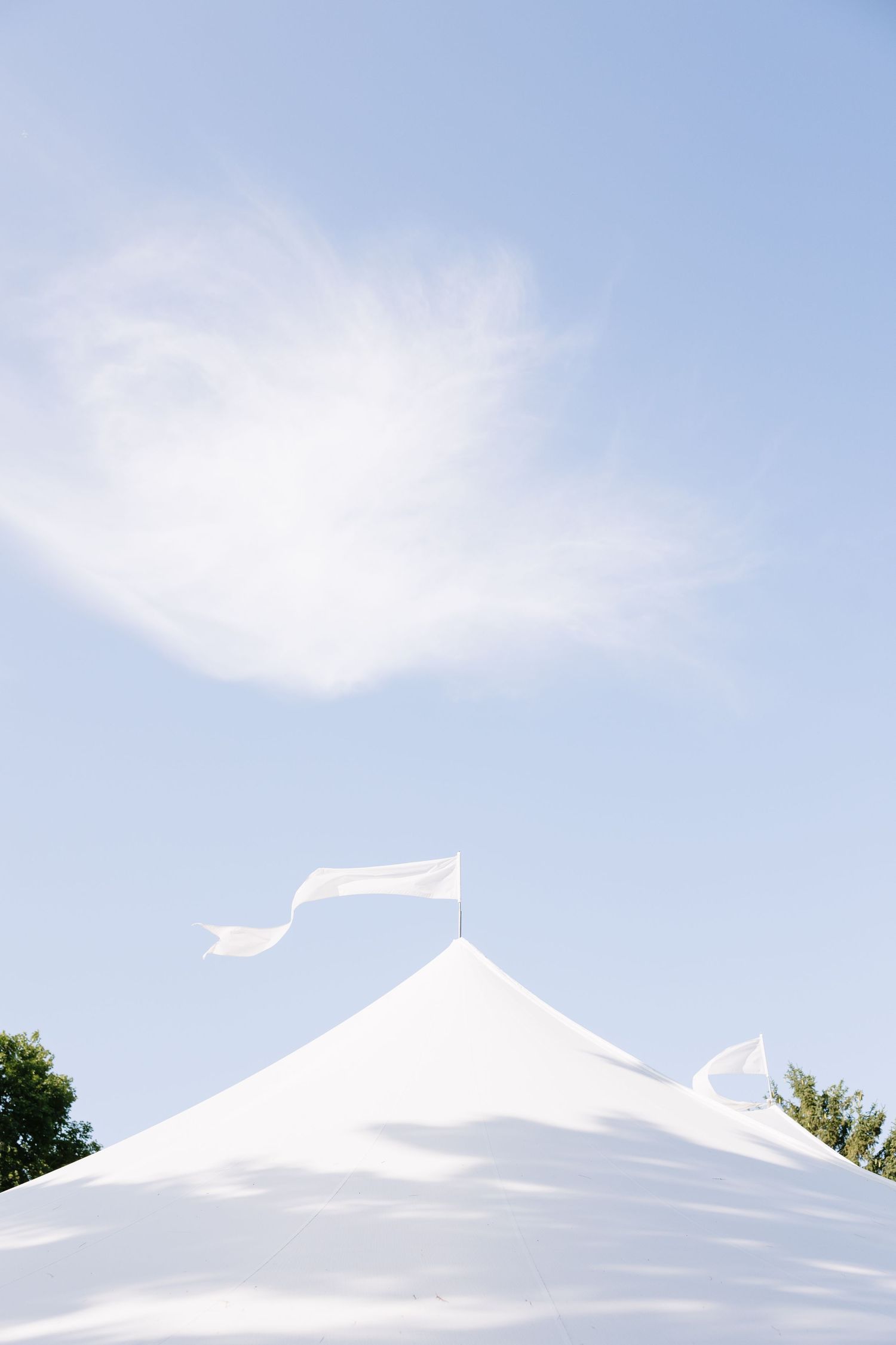 White tent peaks against a bright blue sky with wispy clouds.