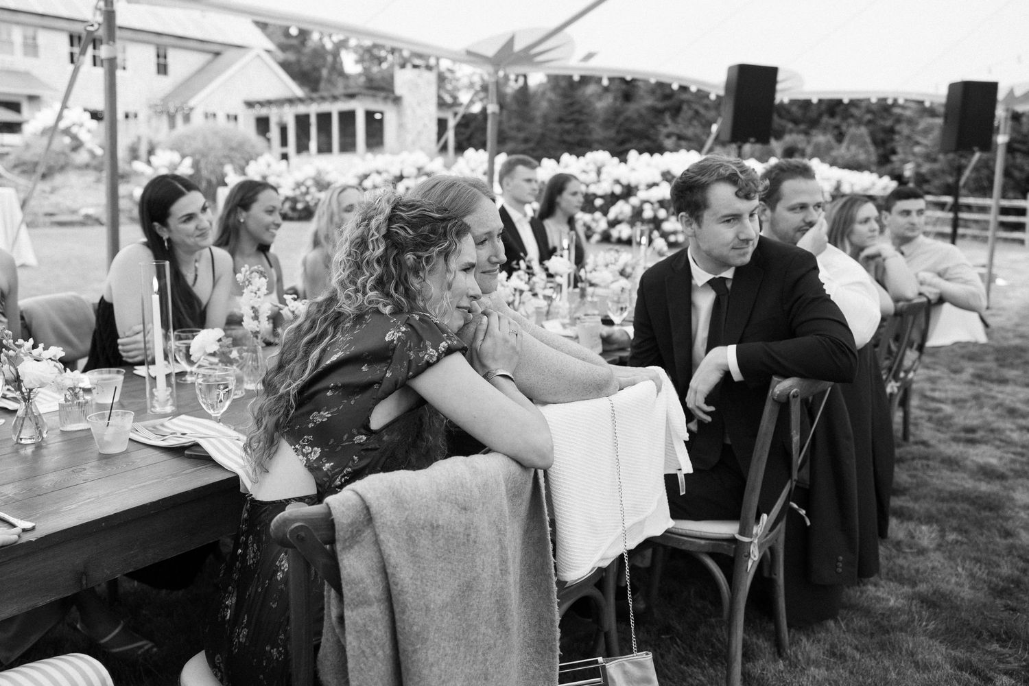 Guests seated at outdoor wedding reception tables in black and white photo.
