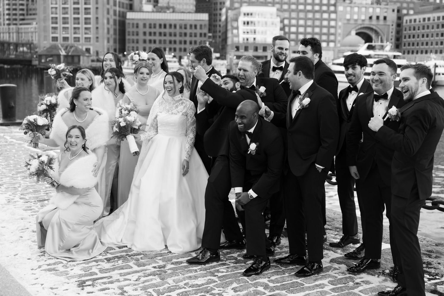 Wedding party poses for photos along a city skyline backdrop.