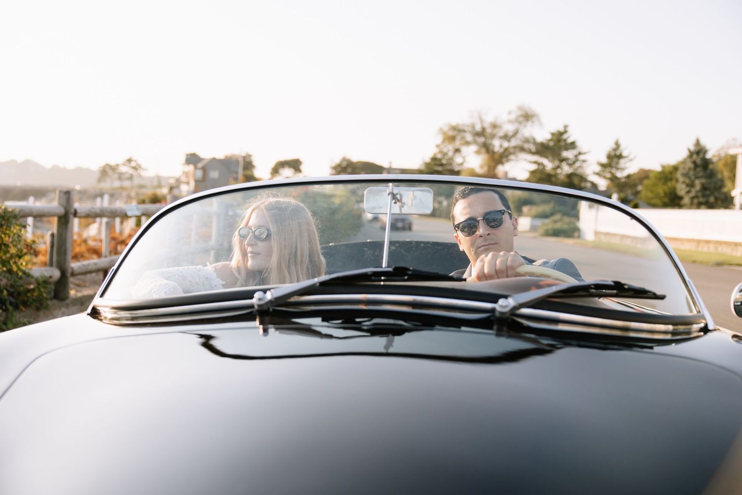 A panoramic view through the windshield of a classic car with mountains in the background.