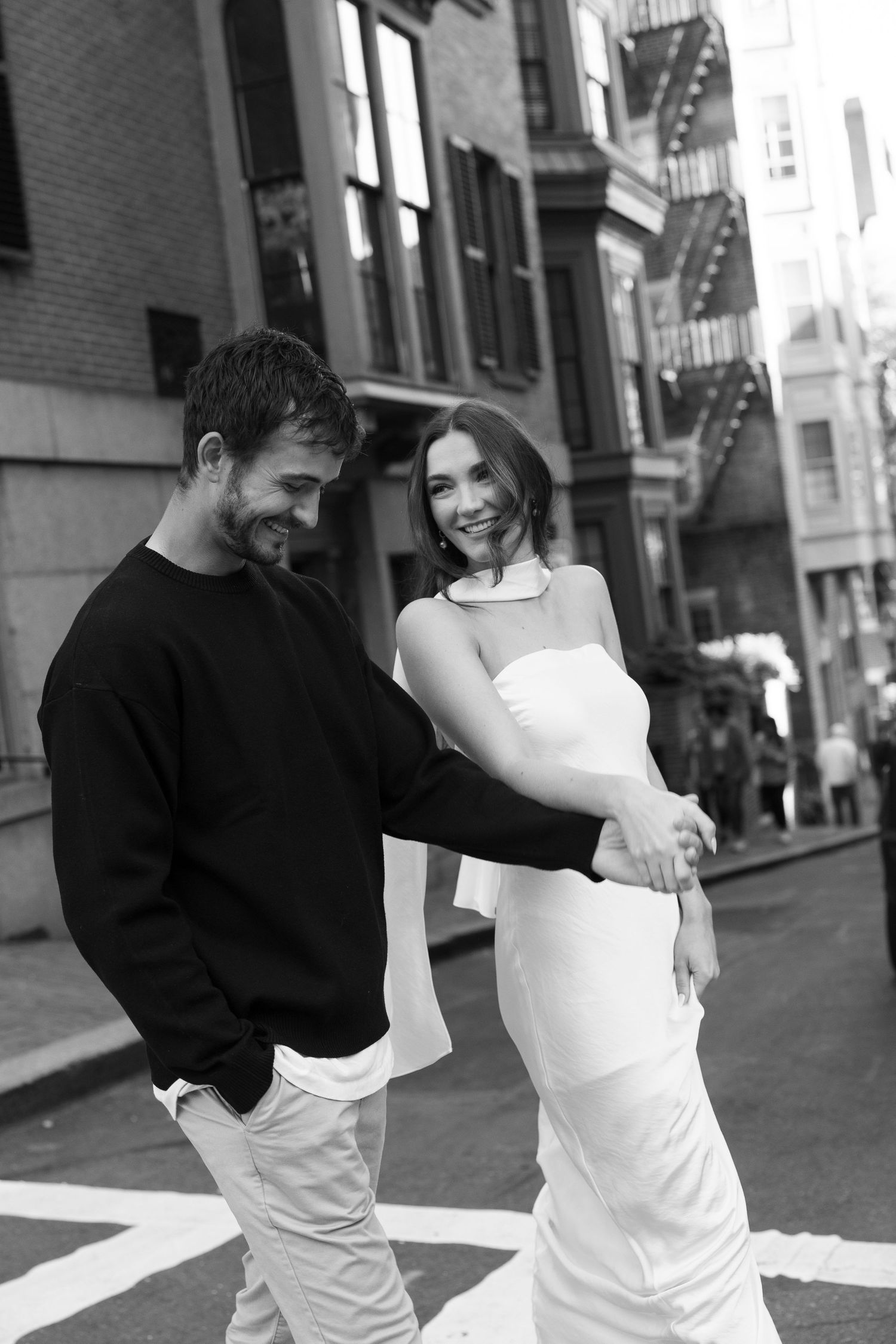Black and white street photo of a couple sharing a candid laughing moment.
