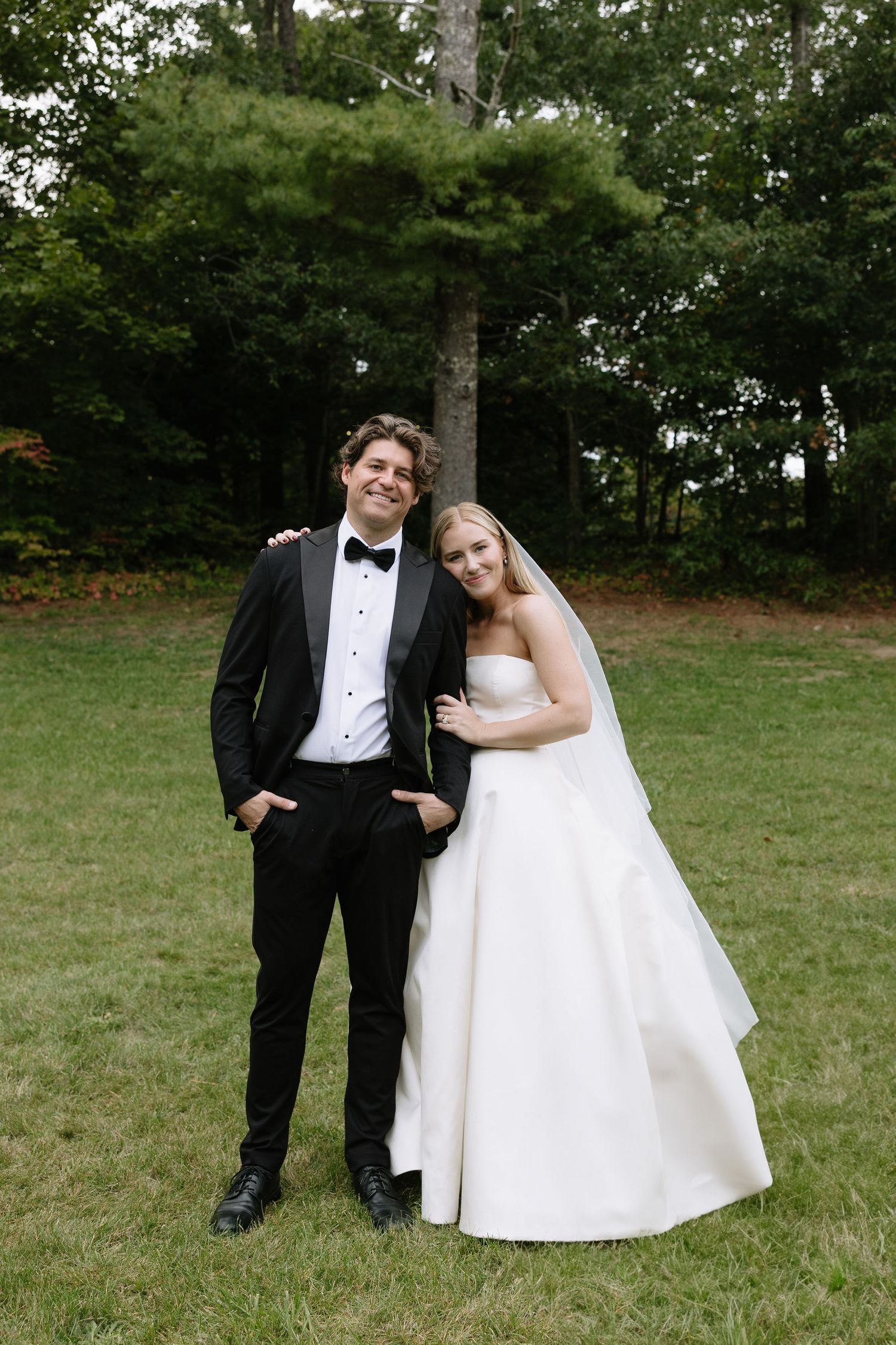 Playful wedding portraits of a couple posing casually on grass.