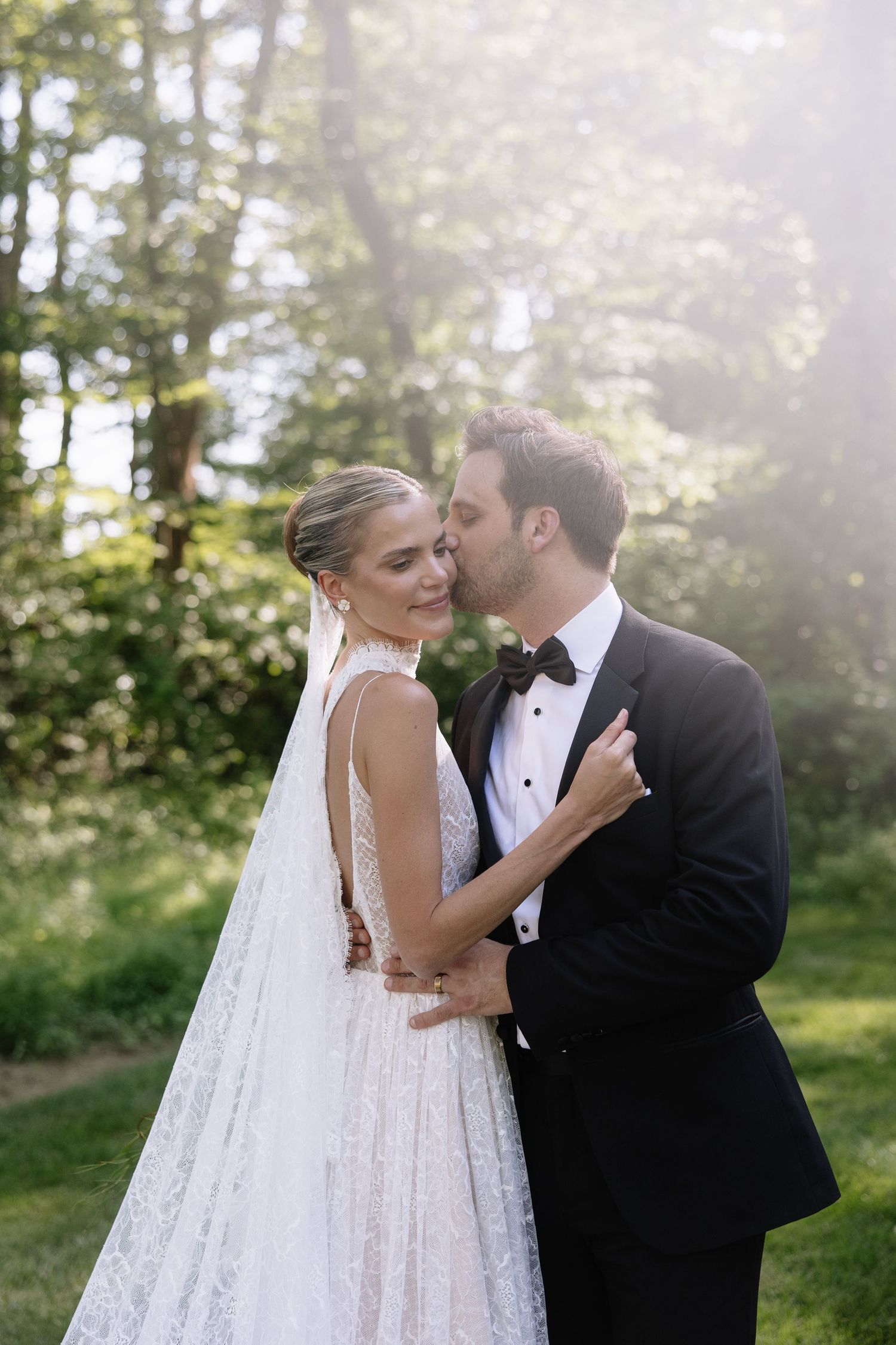 Romantic wedding couple shares tender moment in afternoon sunlight.