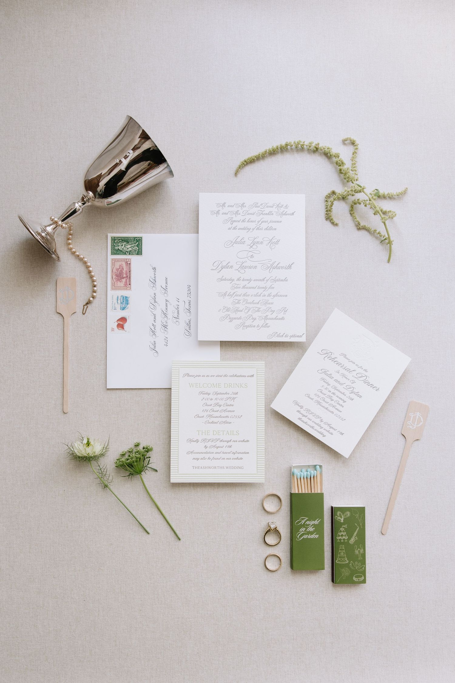 Wedding stationery and accessories artfully arranged on light grey background.