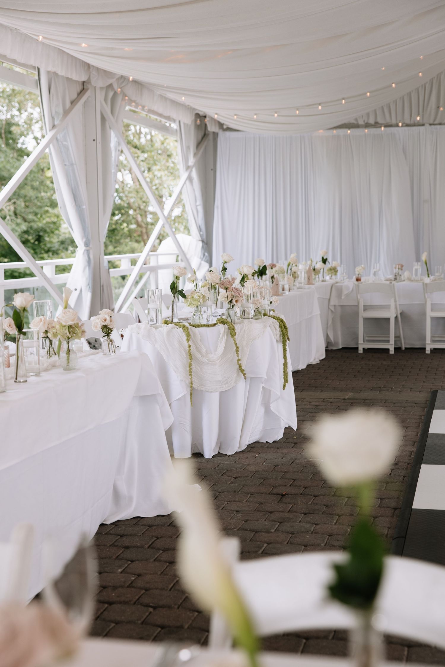Elegant white wedding reception tent setup with draped fabric and table settings.