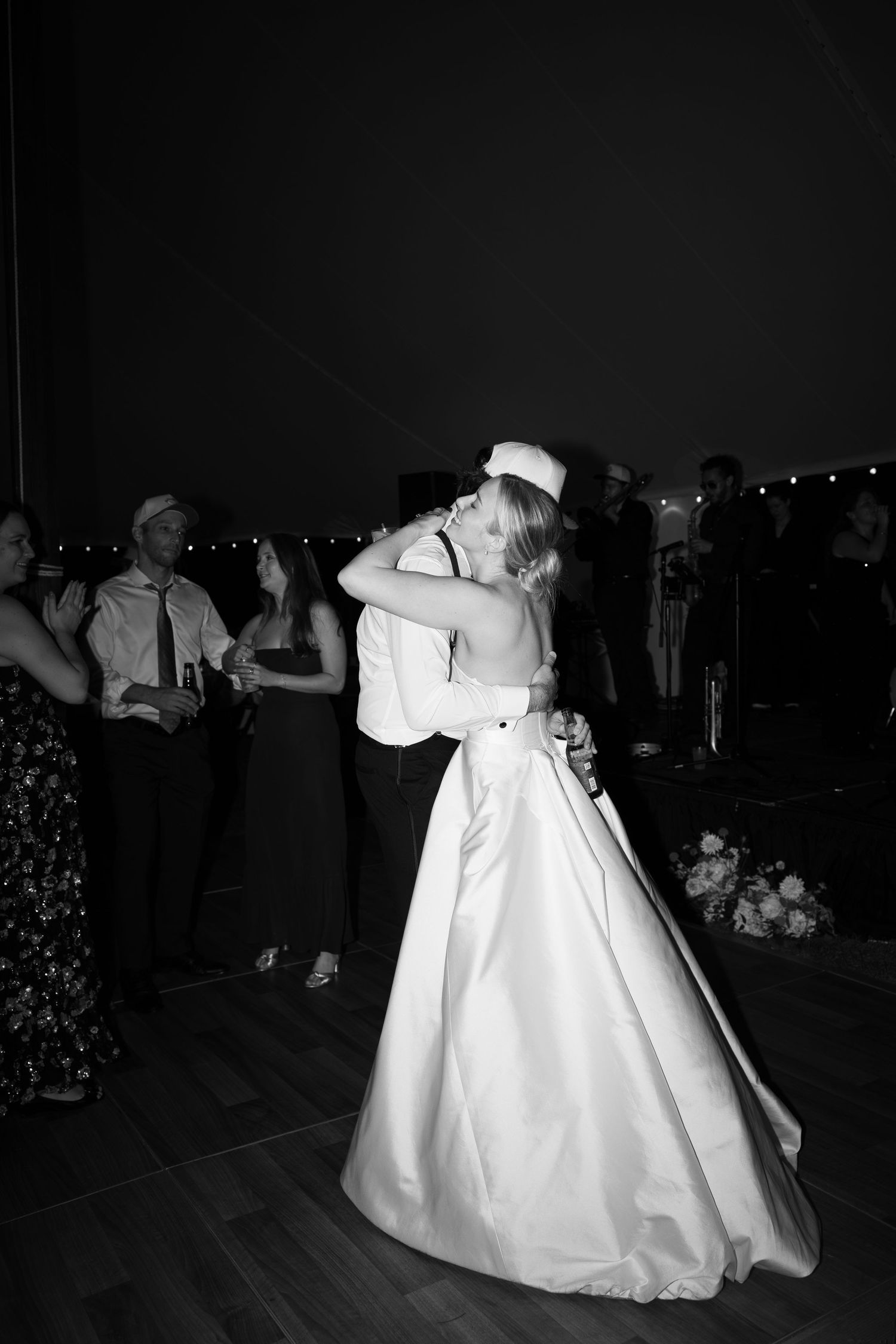 Couple shares romantic dance in elegant wedding attire on darkened dance floor.