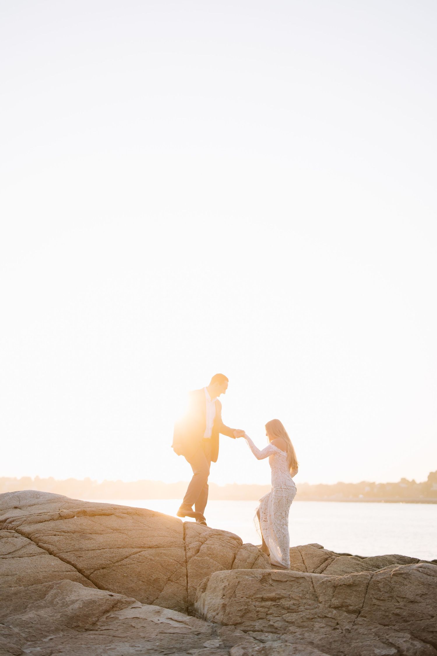 Silhouettes of a couple walking on rocky terrain during golden sunset.