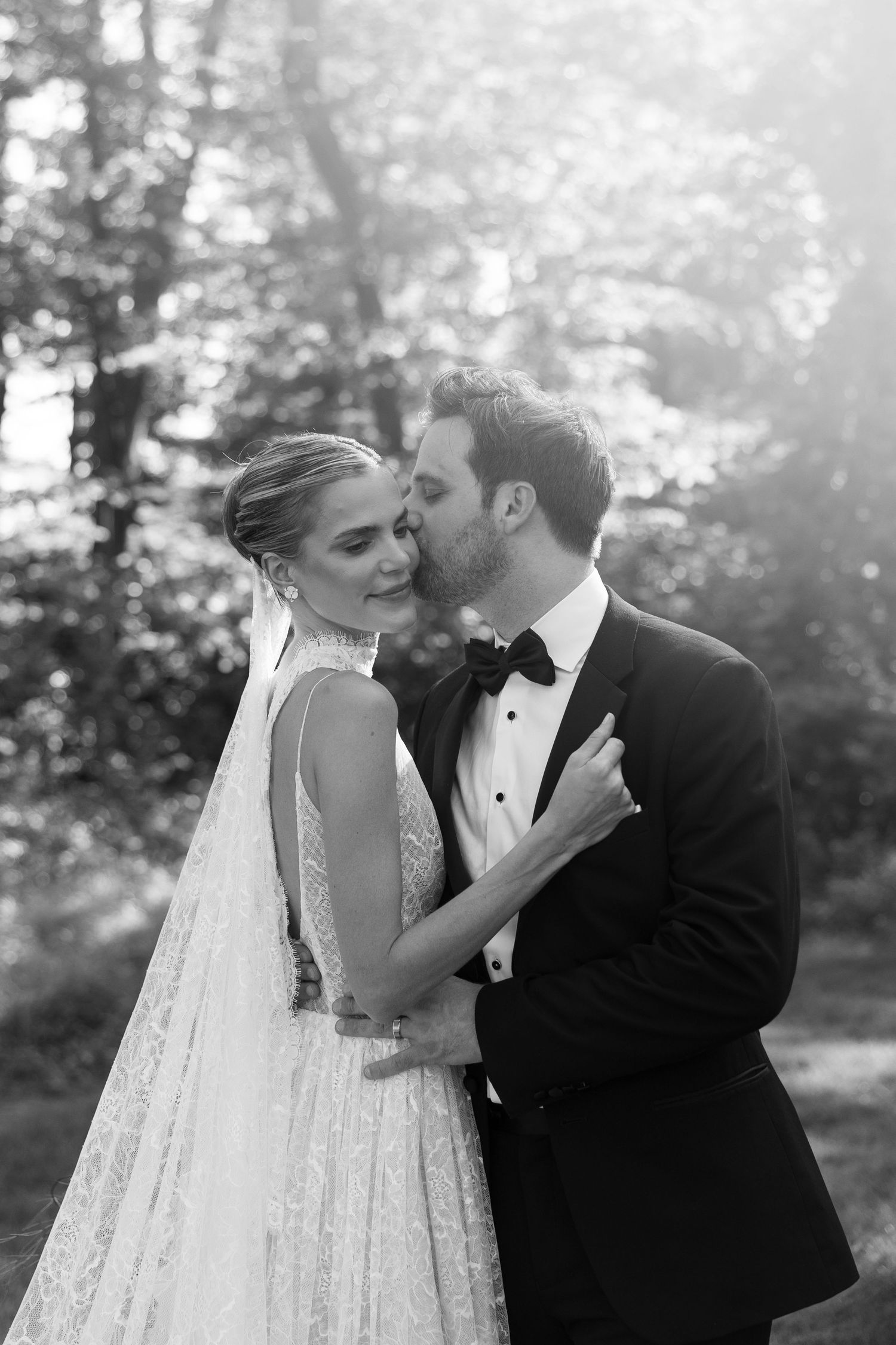 Black and white wedding portraits showing tender moments between newlyweds in a natural setting.