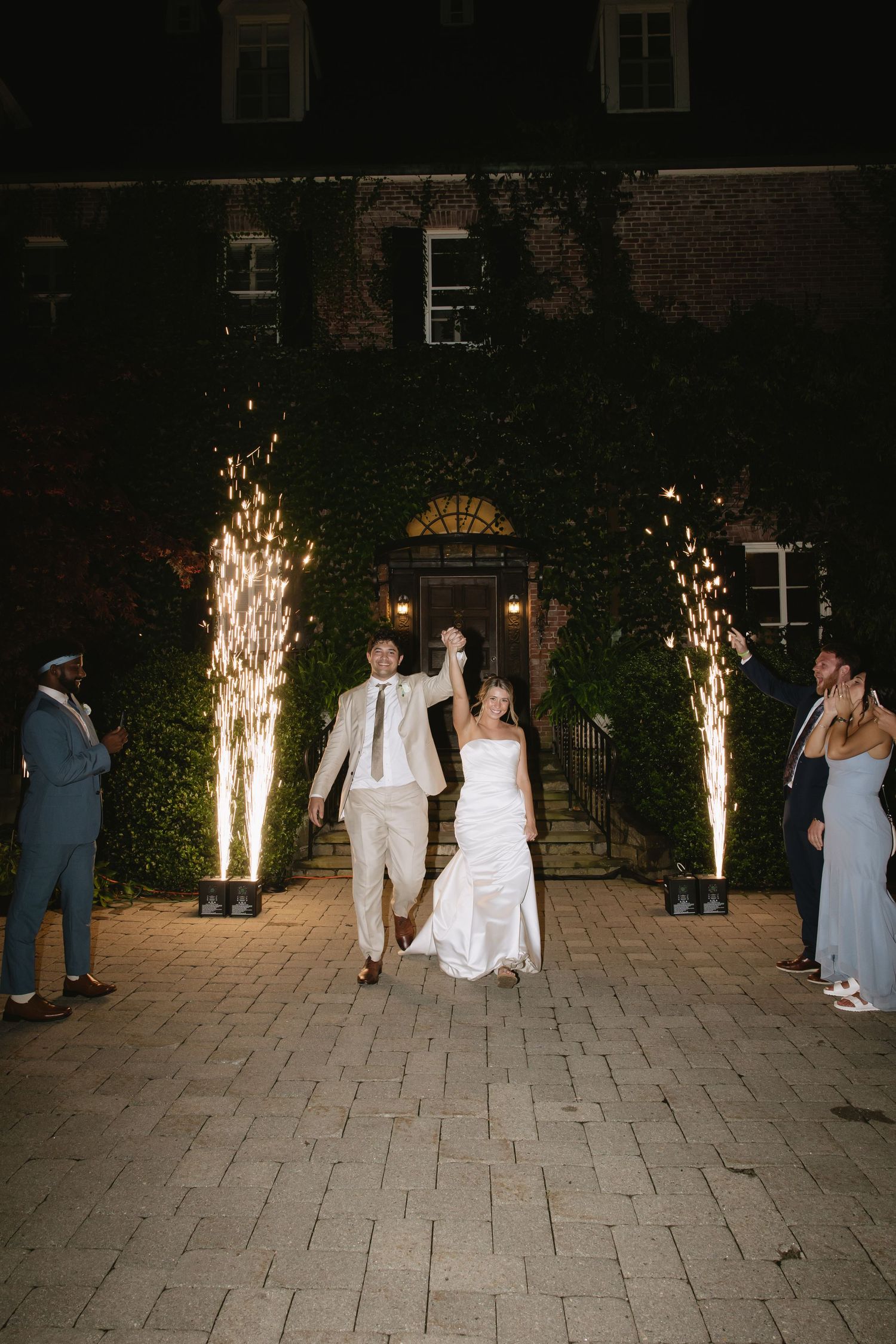 Couple dancing on stone patio with sparkler fountains illuminating the night.