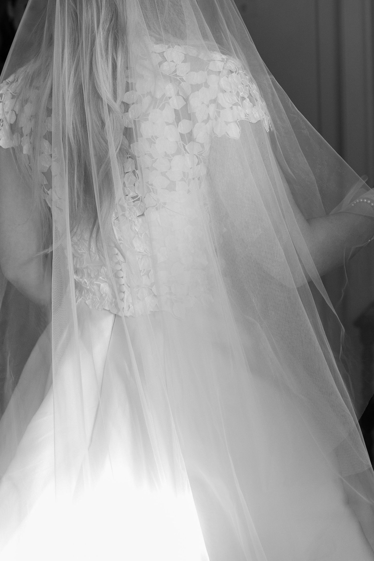 Close-up details of a white wedding dress with lace and tulle fabric.
