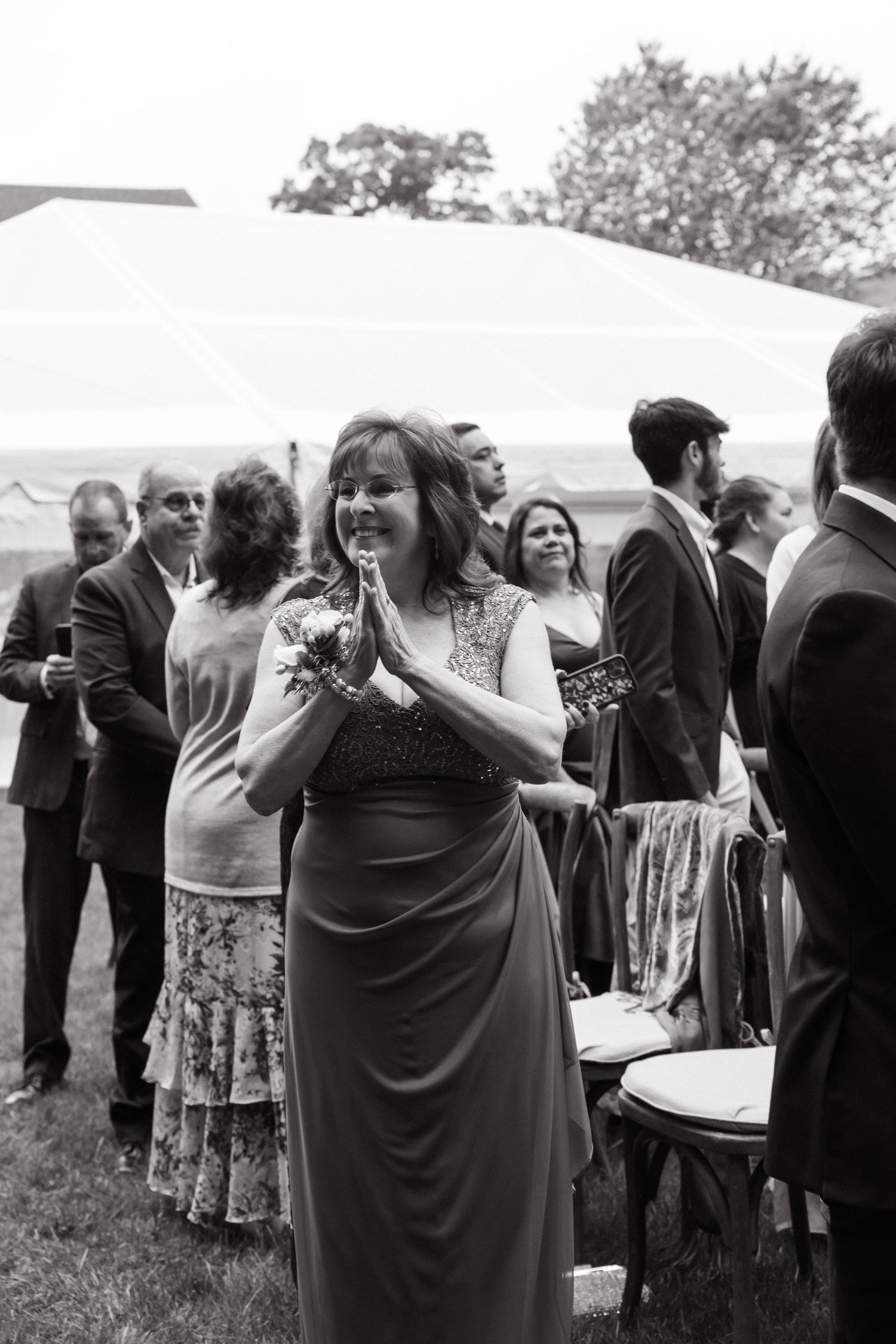 A wedding guest in a formal gown reacts with joy during an outdoor reception.