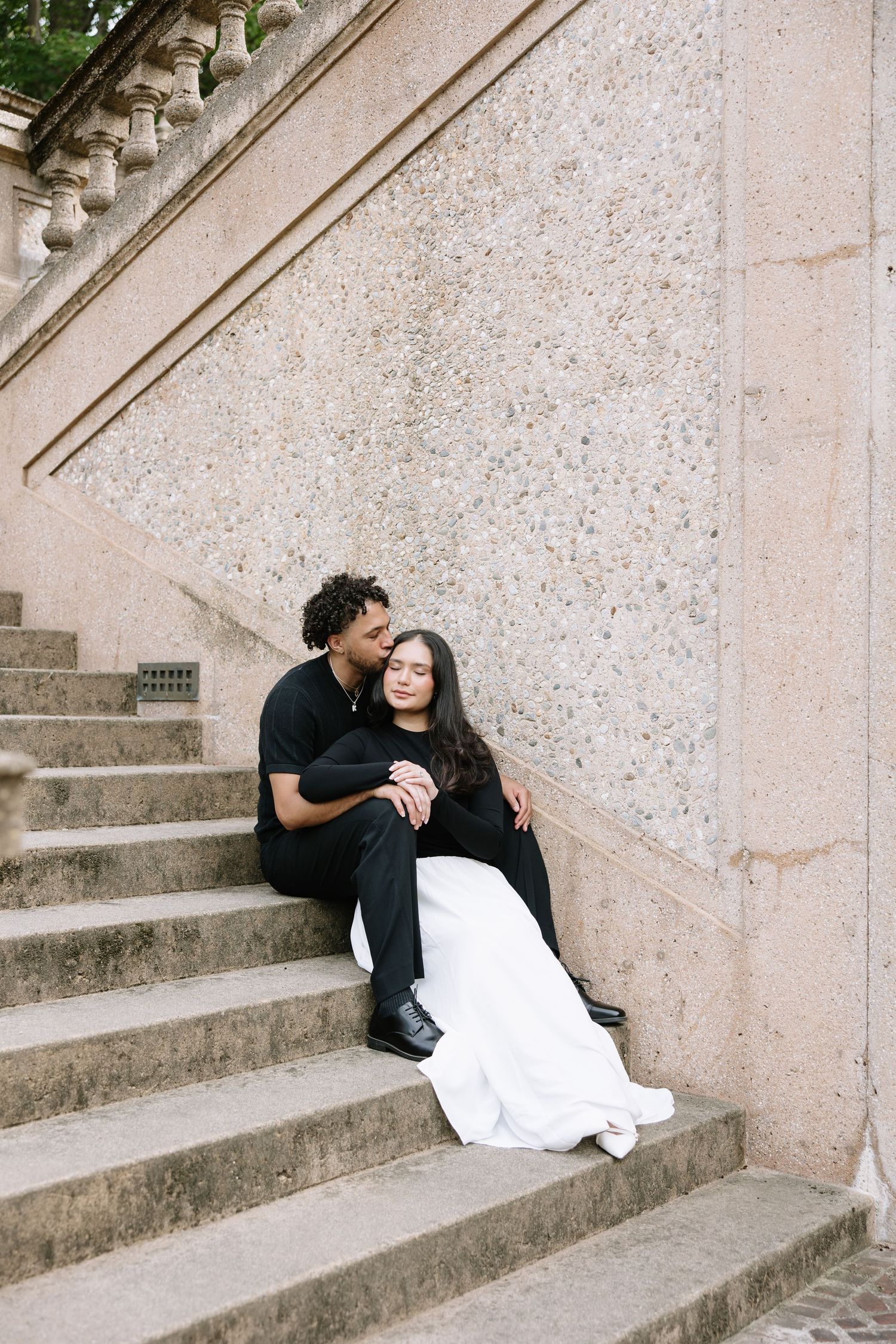 A couple relaxes on stone steps while sharing a tender moment.