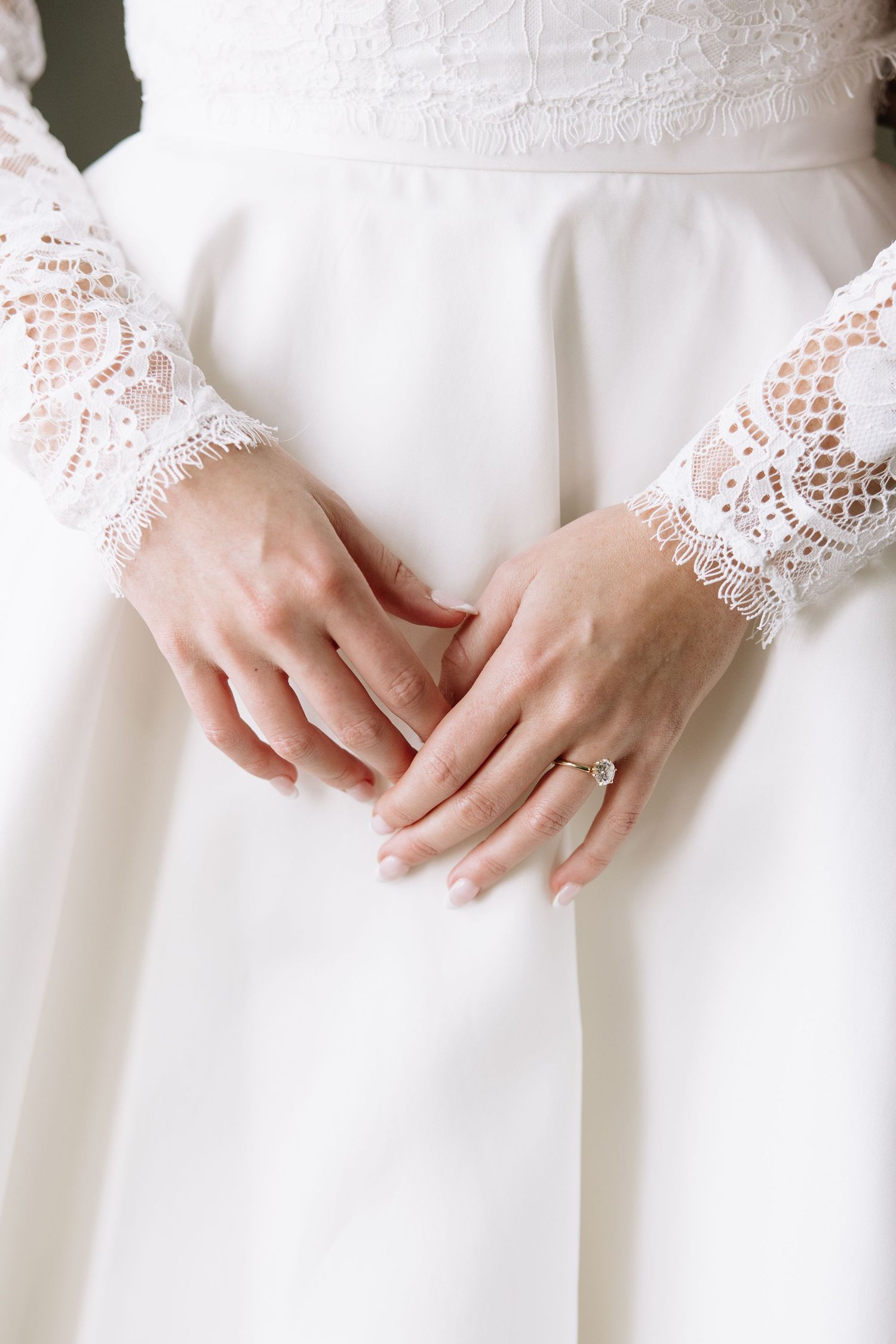Close-up detail of delicate lace sleeves on a white wedding dress.