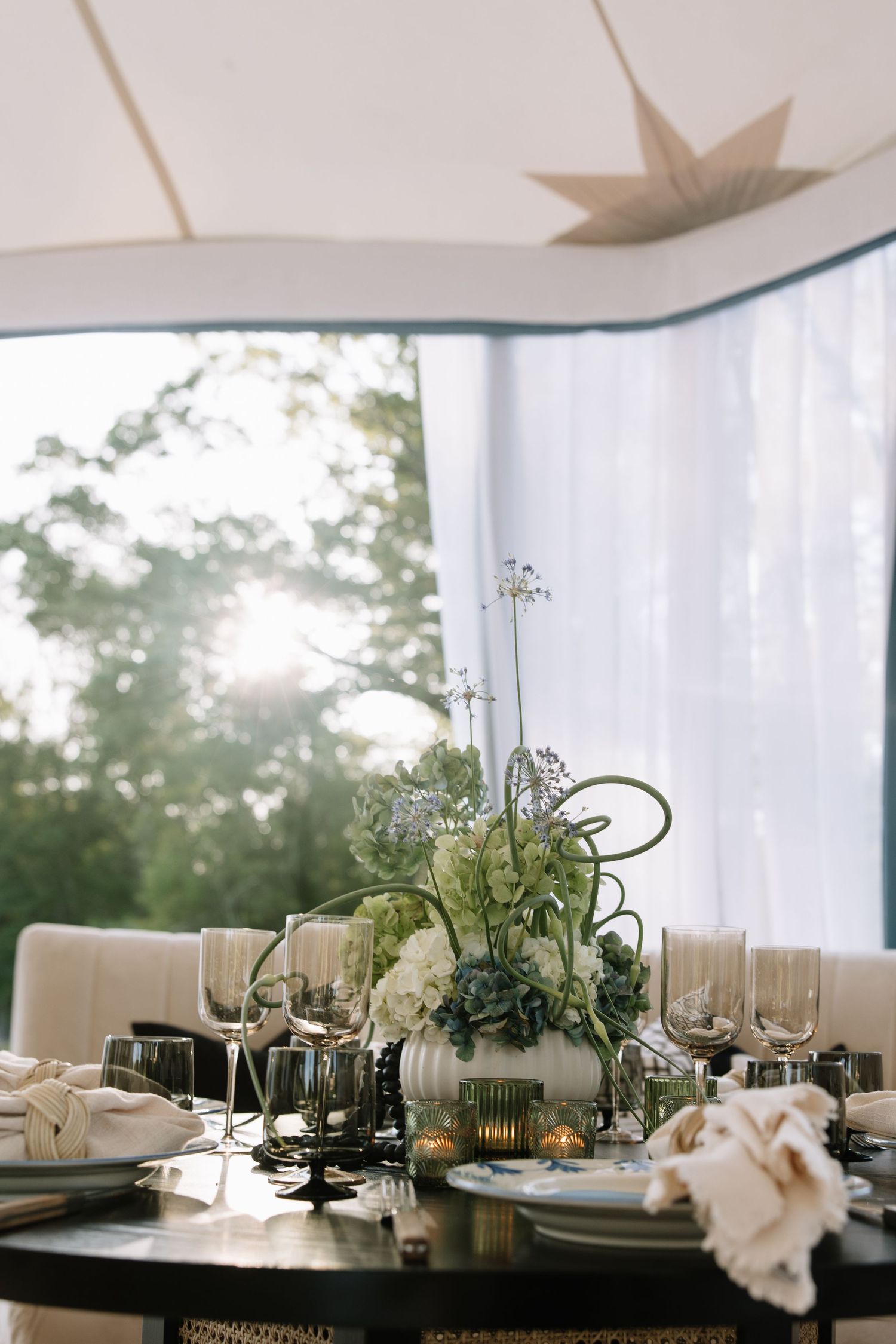 Elegant wedding reception table setting with white linens and modern centerpieces under draped fabric.