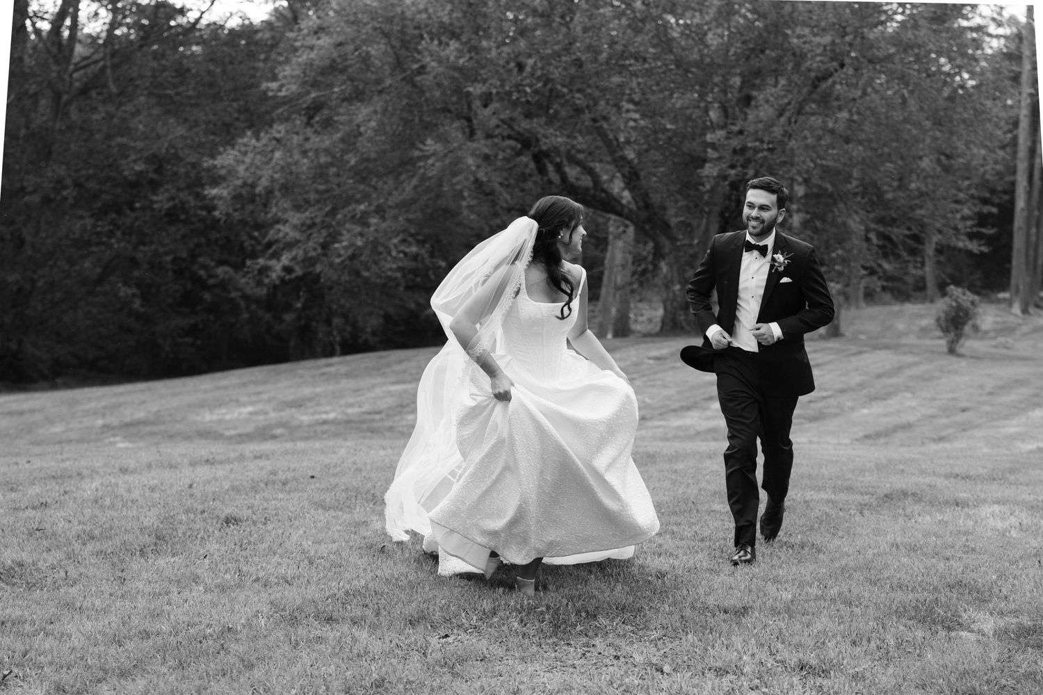 Wedding couple walks together across a scenic outdoor setting in black and white.