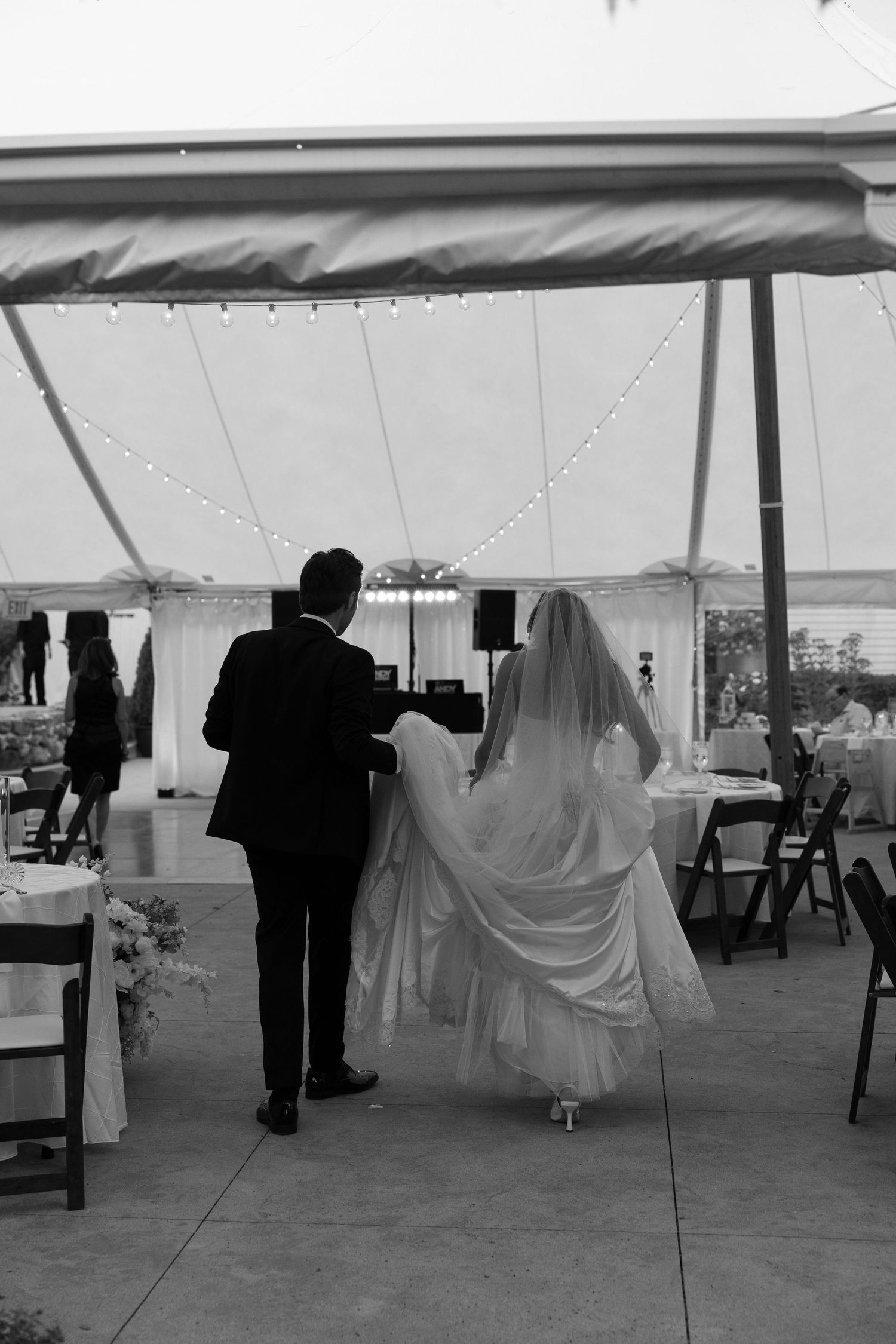 Black and white photo of wedding reception setup inside an elegant white tent.