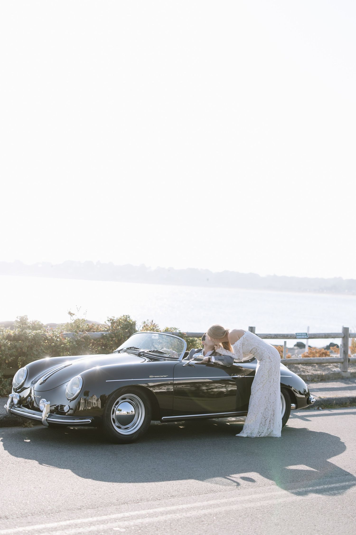 Elegant vintage black convertible cars displayed in a parking area by the ocean.