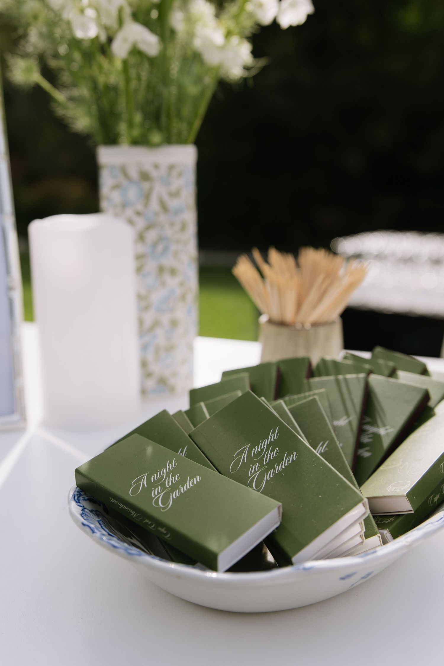 Elegant green wedding programs displayed in white dishes with floral centerpieces.