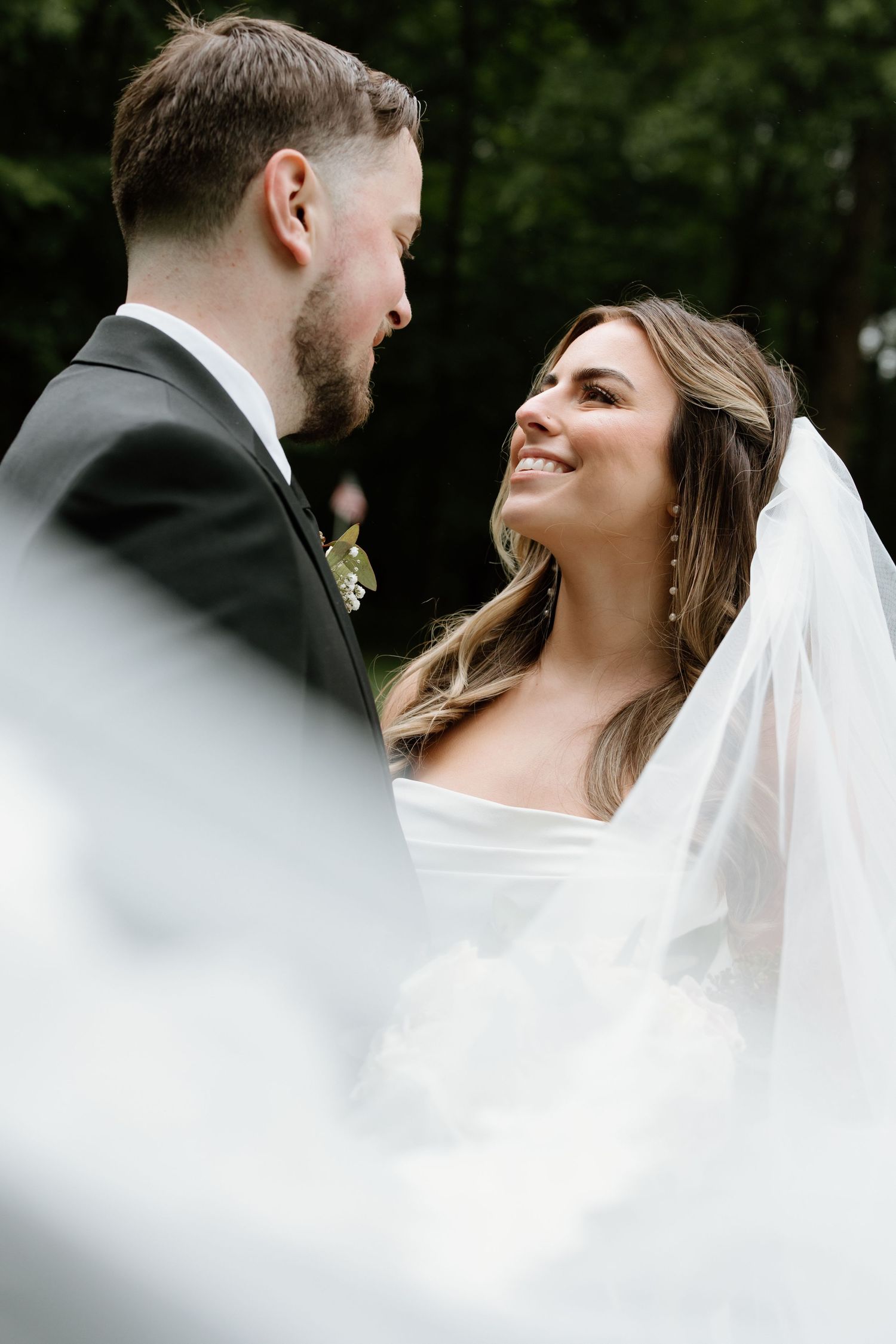 Close-up portrait of couple sharing intimate moment through wedding veil.