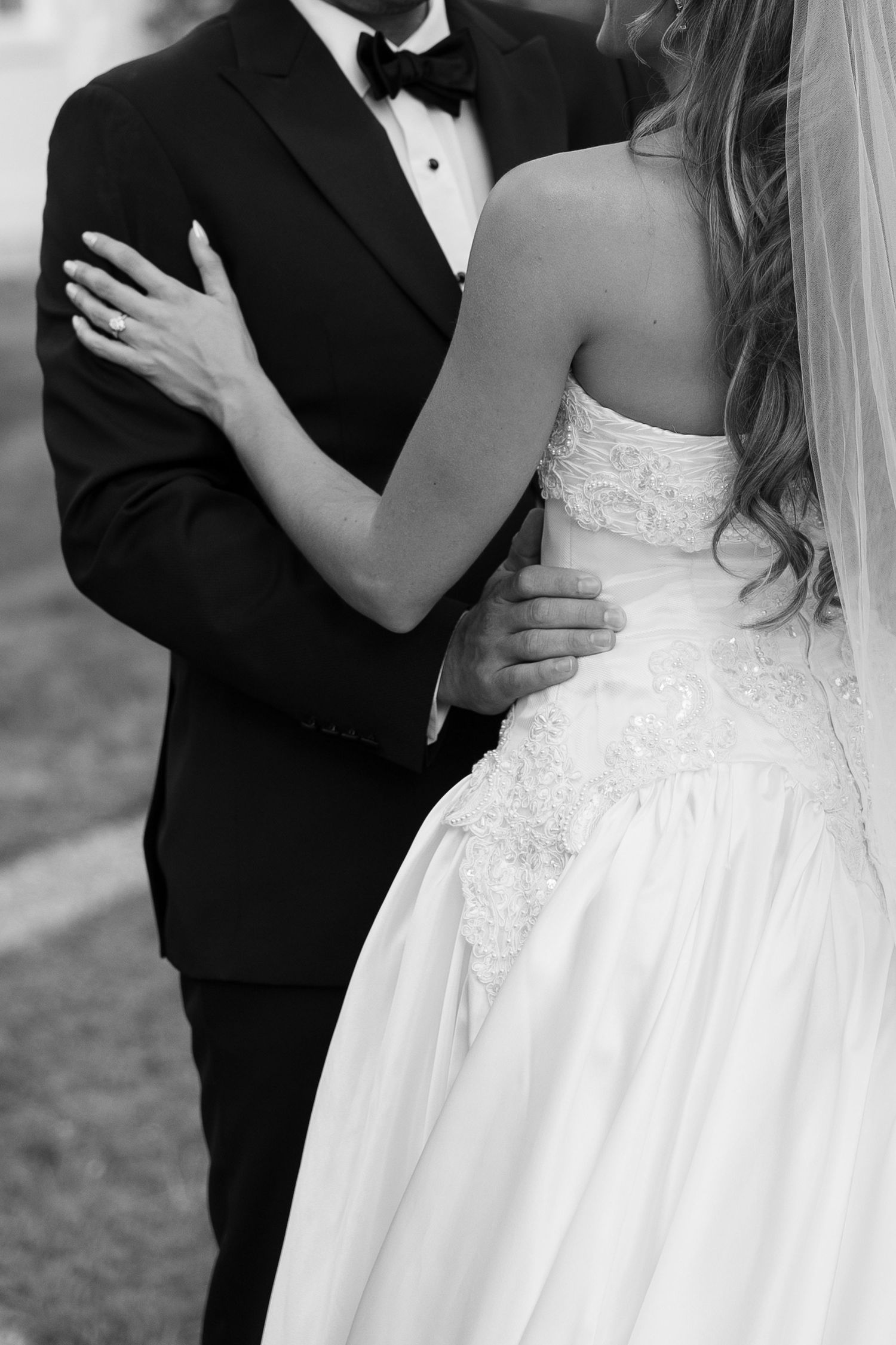 Close-up details of a bride's white lace wedding gown during outdoor photography session.