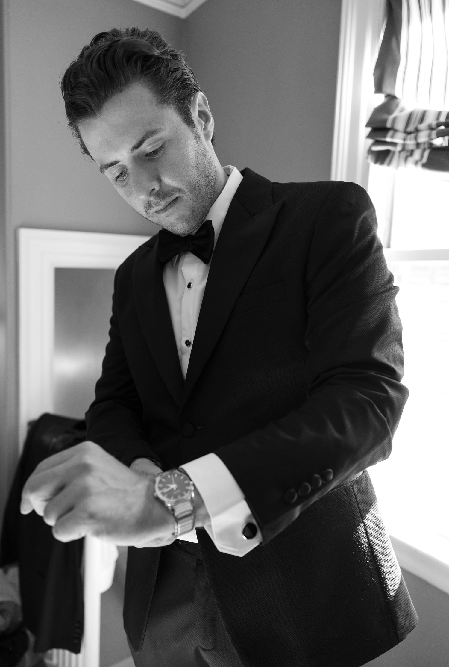 Black and white series of groom adjusting his tuxedo before ceremony.