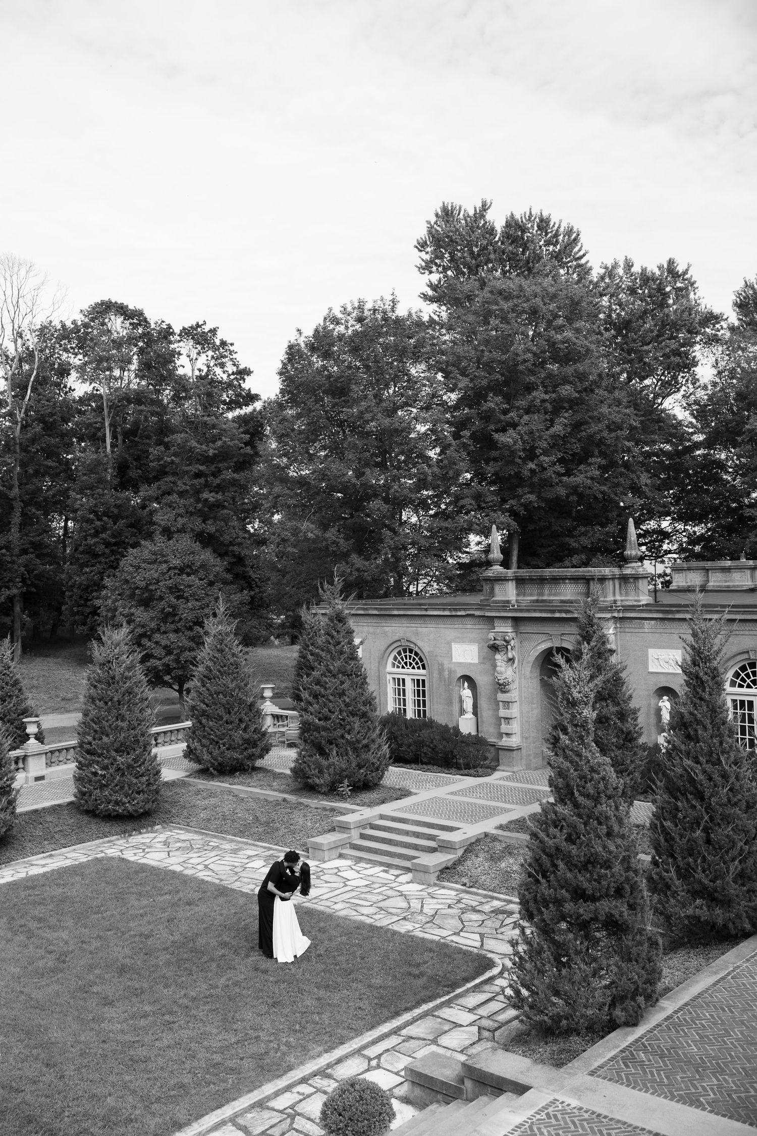 Black and white view of a formal garden terrace with architectural elements and evergreens.