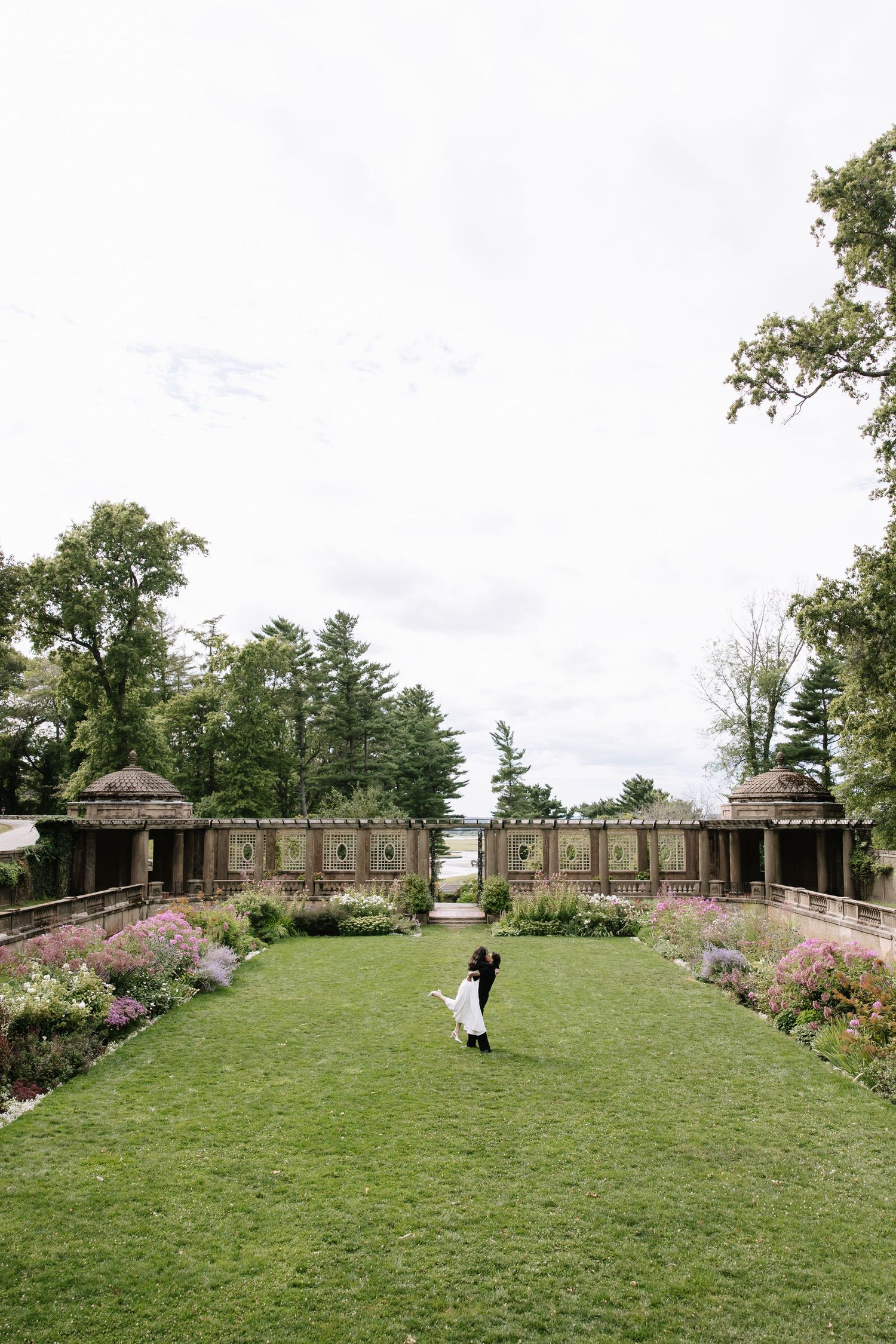 A wide view of a formal garden with stone structures and manicured lawns.