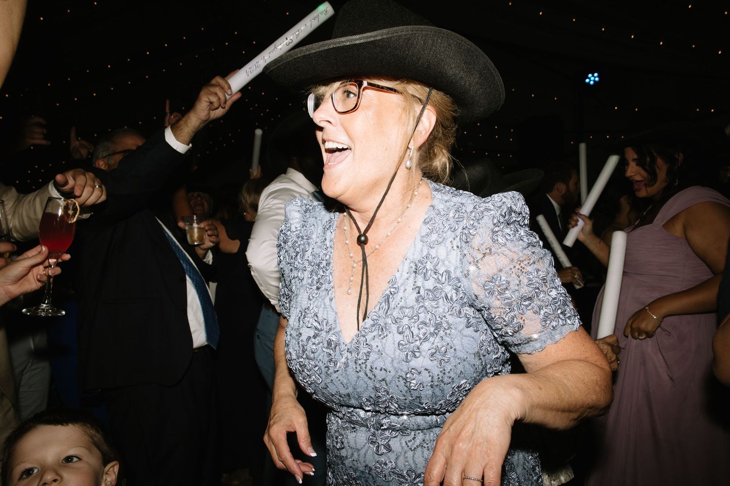 Person in sparkly dress and cowboy hat dancing at nighttime celebration.