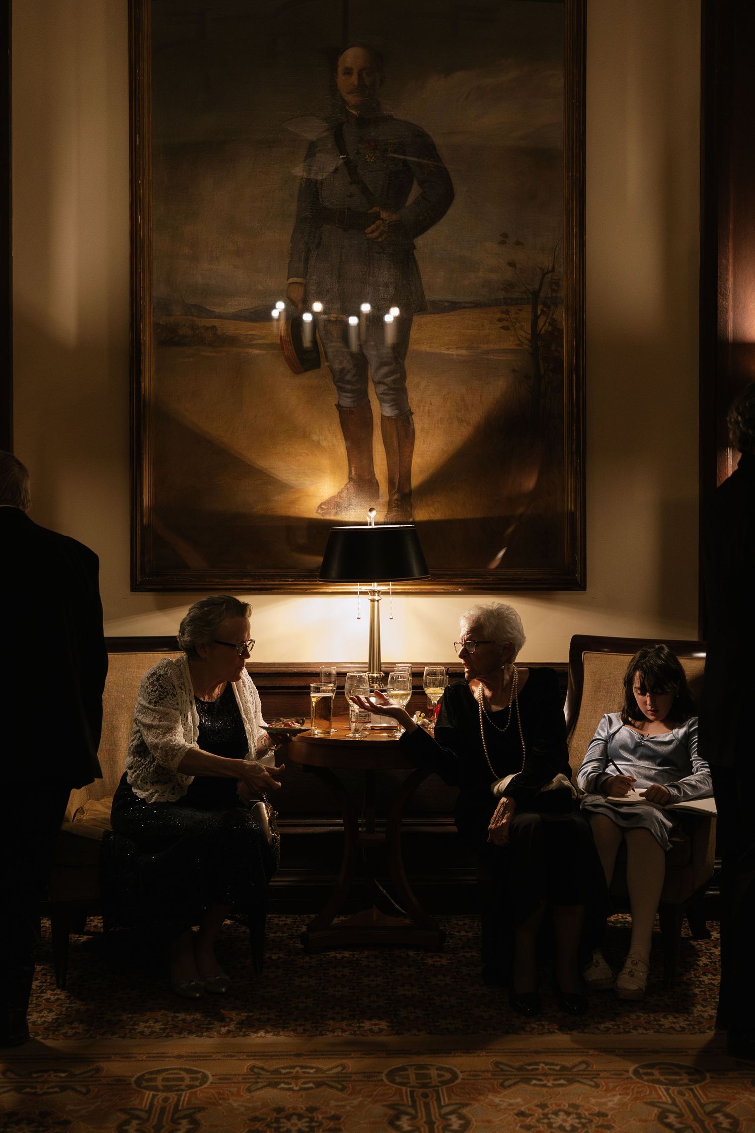 Guests seated in dimly lit room with table lamps and artwork on walls.