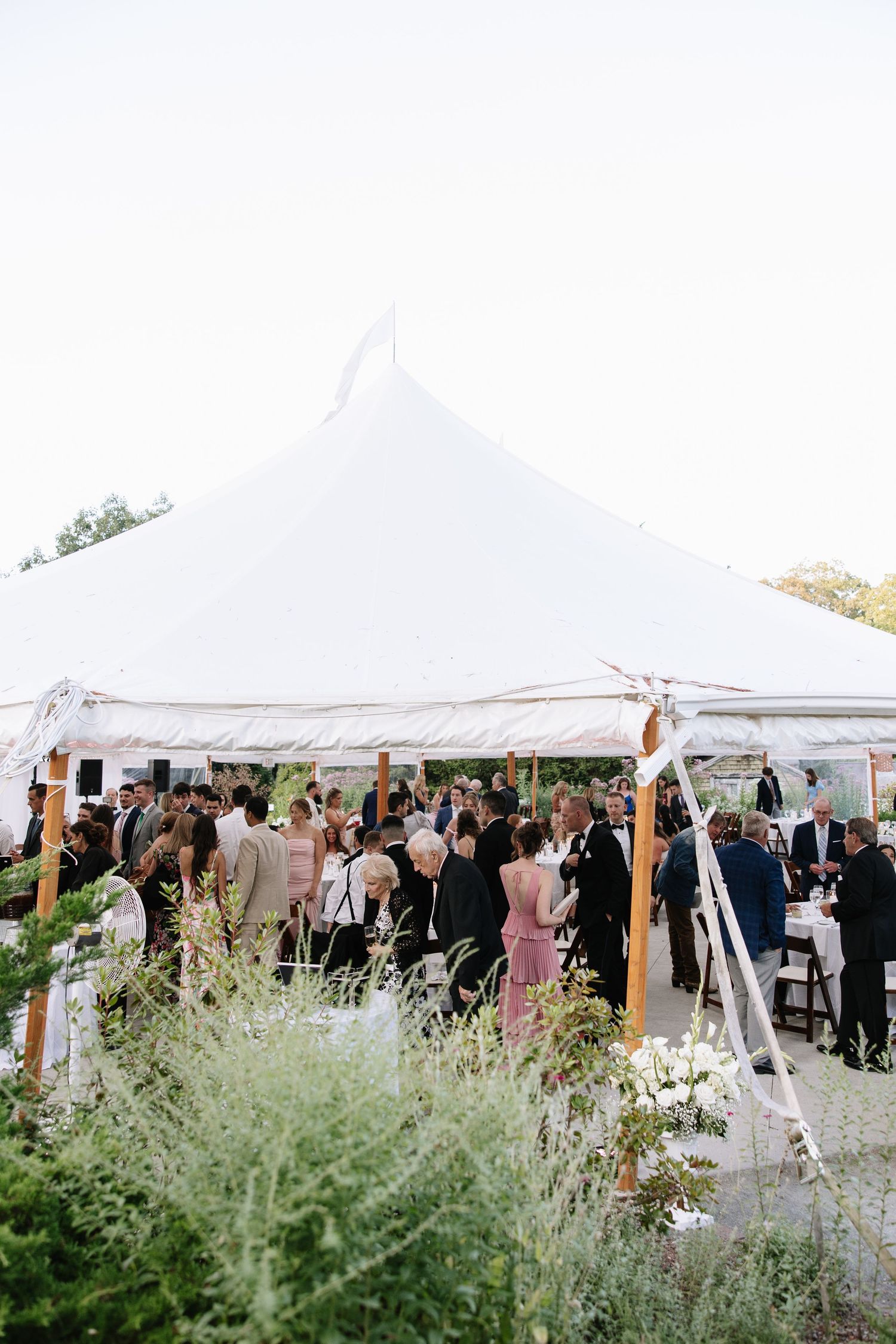 Wedding reception under white tents with wildflower garden decorations.