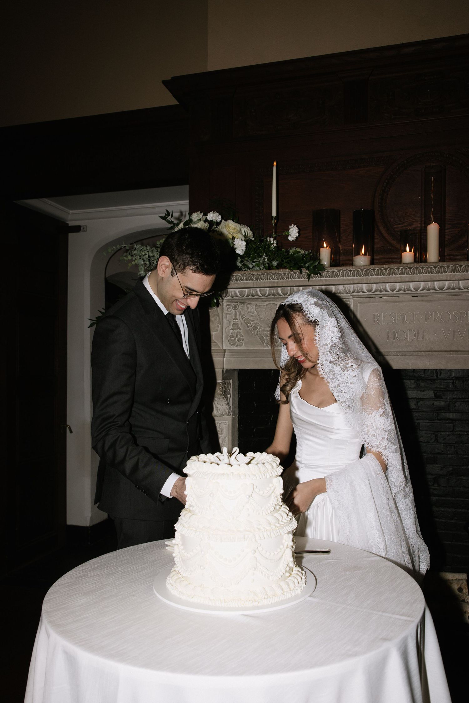 Wedding couple cutting their elegant white tiered cake at the reception.
