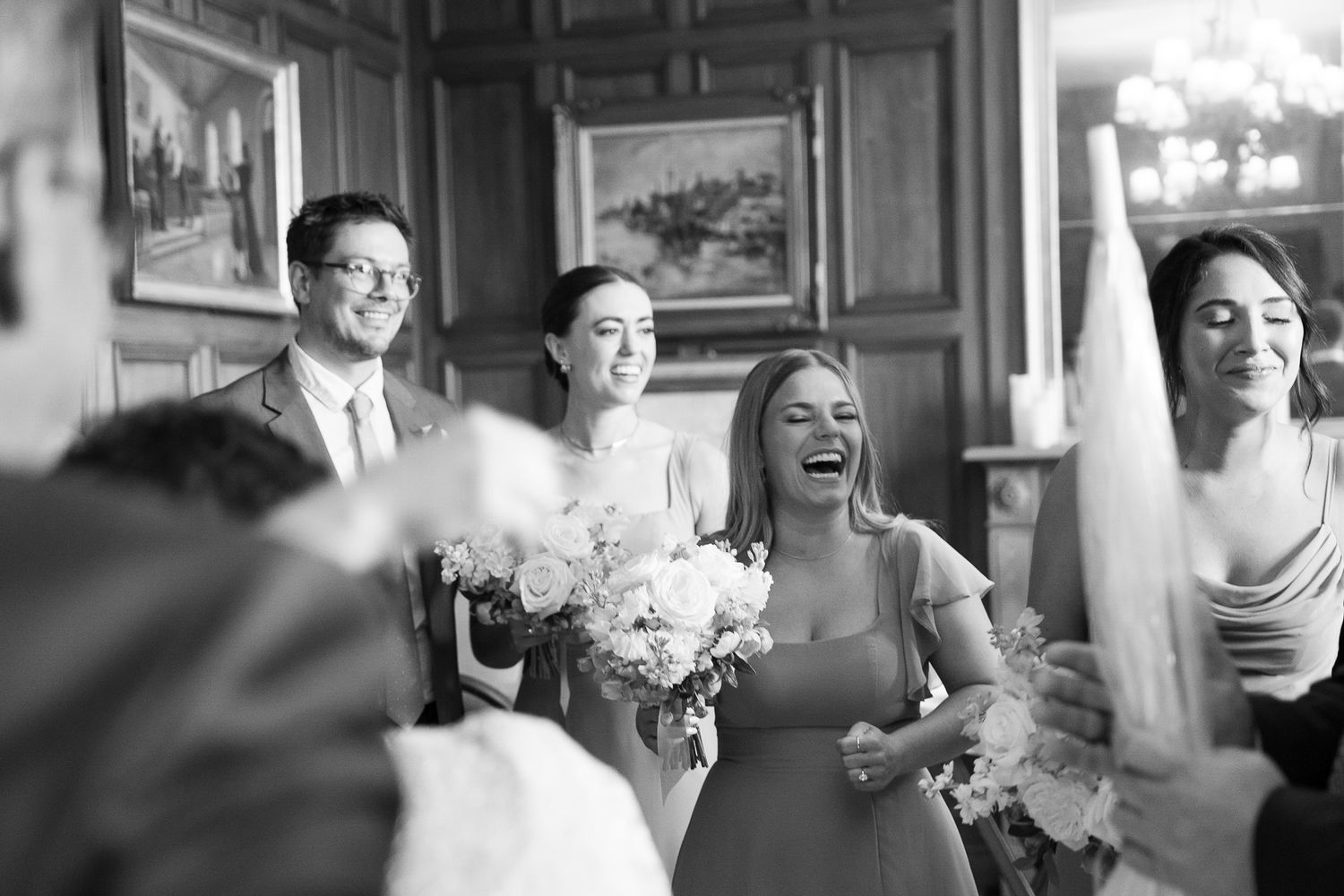 Black and white photo of wedding guests laughing during reception.