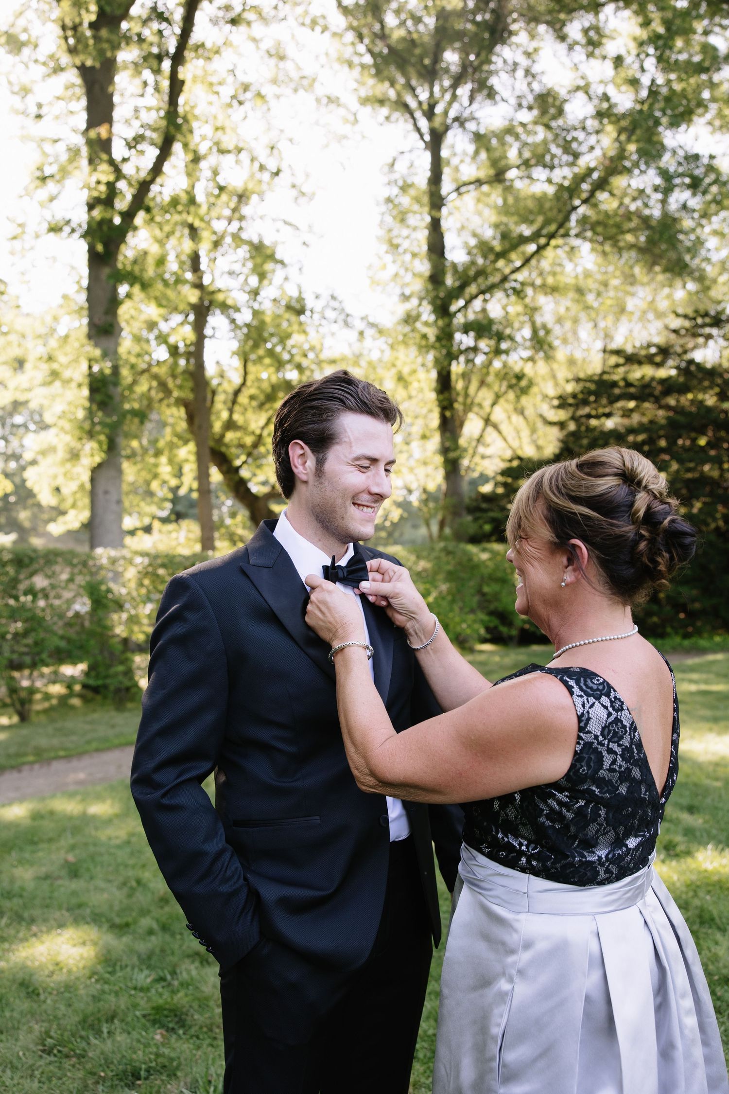 A couple laughs together during their wedding photoshoot in a sunlit garden setting.