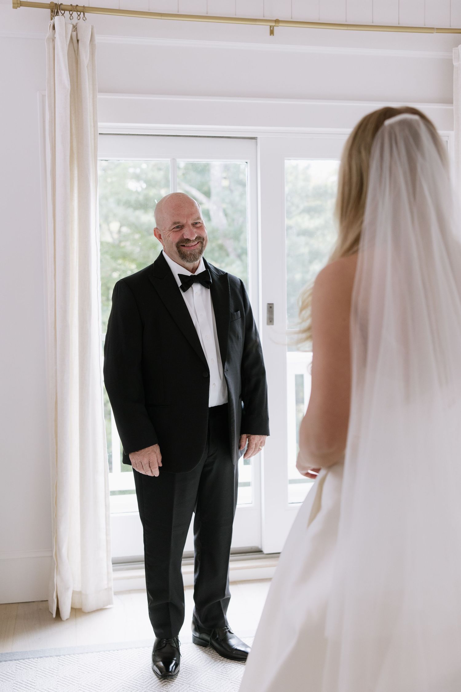 An emotional reveal moment in a bright room with white curtains and natural lighting.