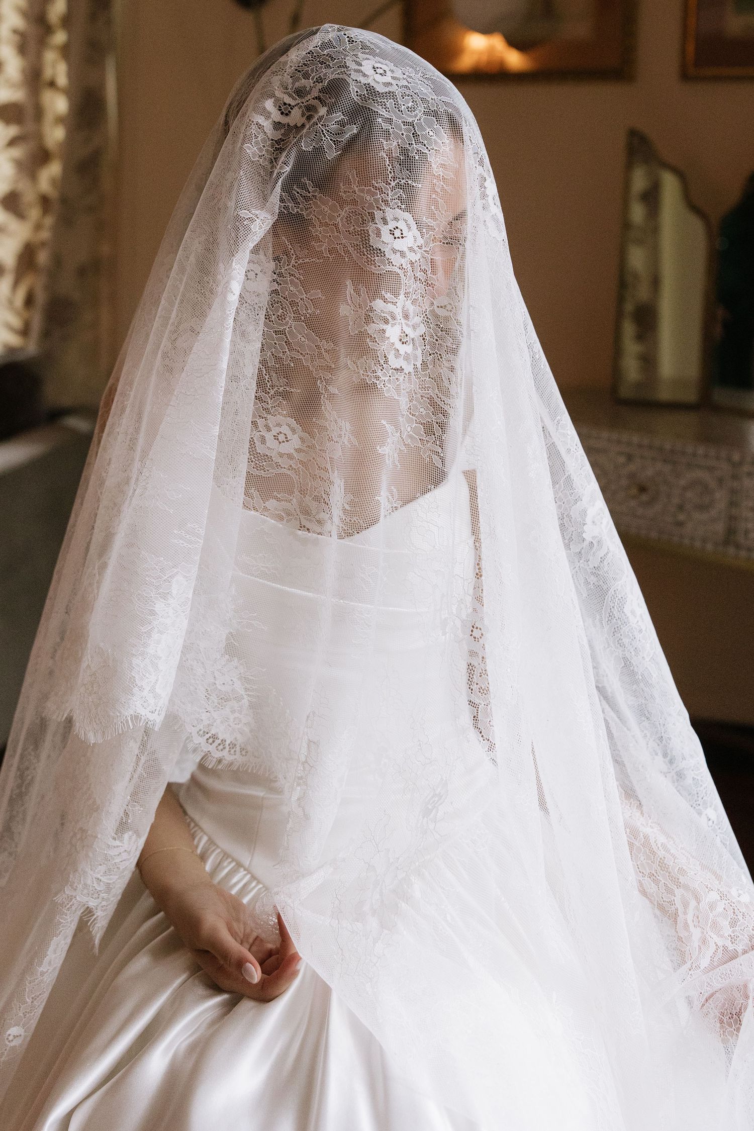 Close-up details of delicate lace wedding veil and white bridal gown.